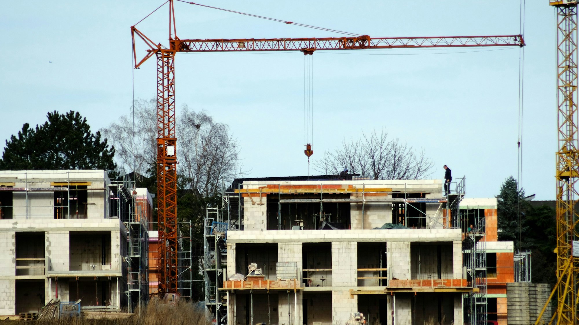 Ein Rohbau ohne Fenster, daneben ein Kran vor blauem Himmel.