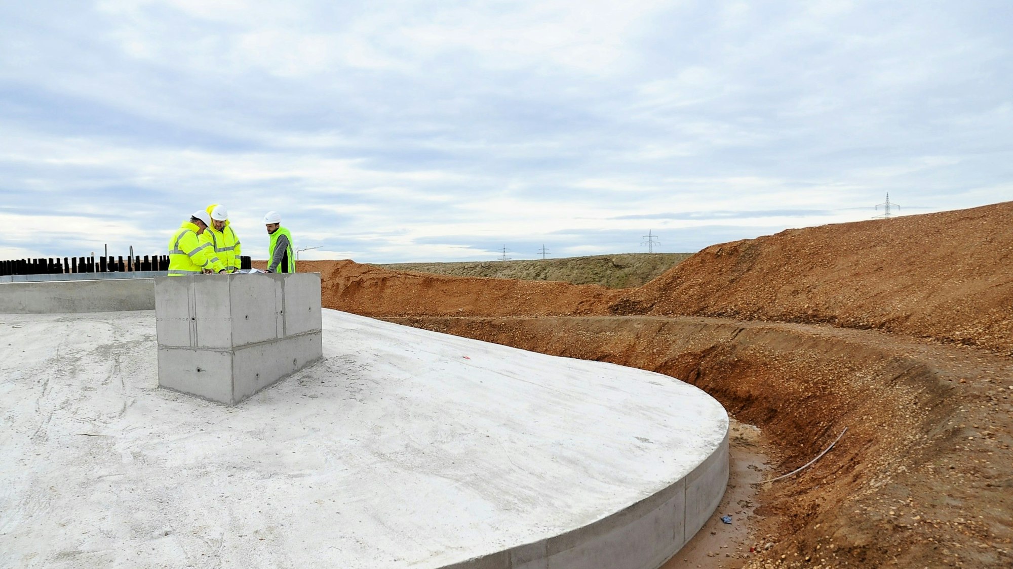 In Erftstadt-Friesheim stehen drei Menschen auf dem Fundament einer Windkraftanlage. Die REA GmbH  baut in Friesheim den Windpark Erftstadt A1. Auf dem Bild Bauleiter Udo Hanisch, Teamleiter Projektentwickler Daniel Rüttgers und Geschäftsführer Klaus Wildrath.