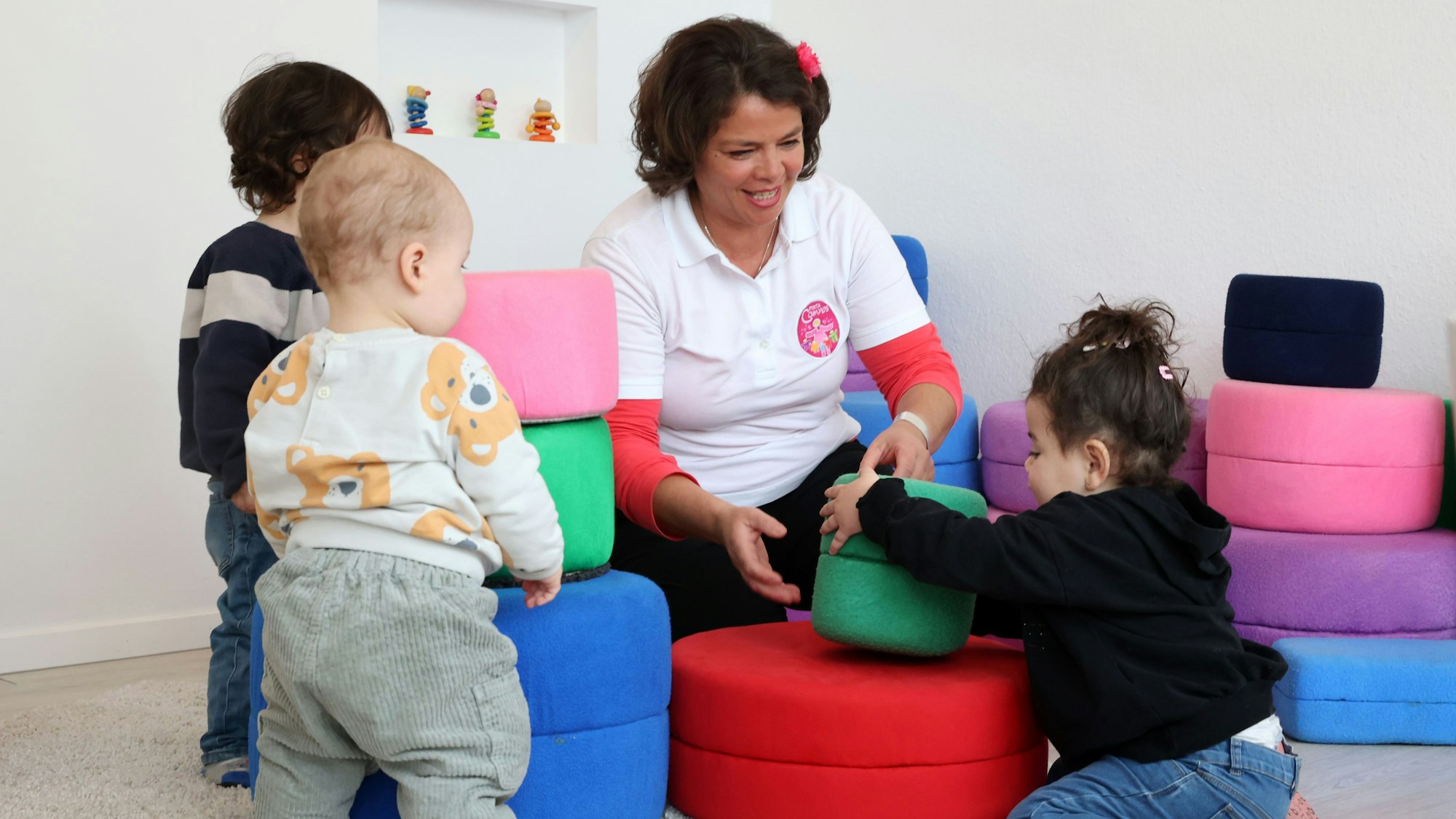 Eine Kindertagespflegerin spielt mit drei Kleinkindern.