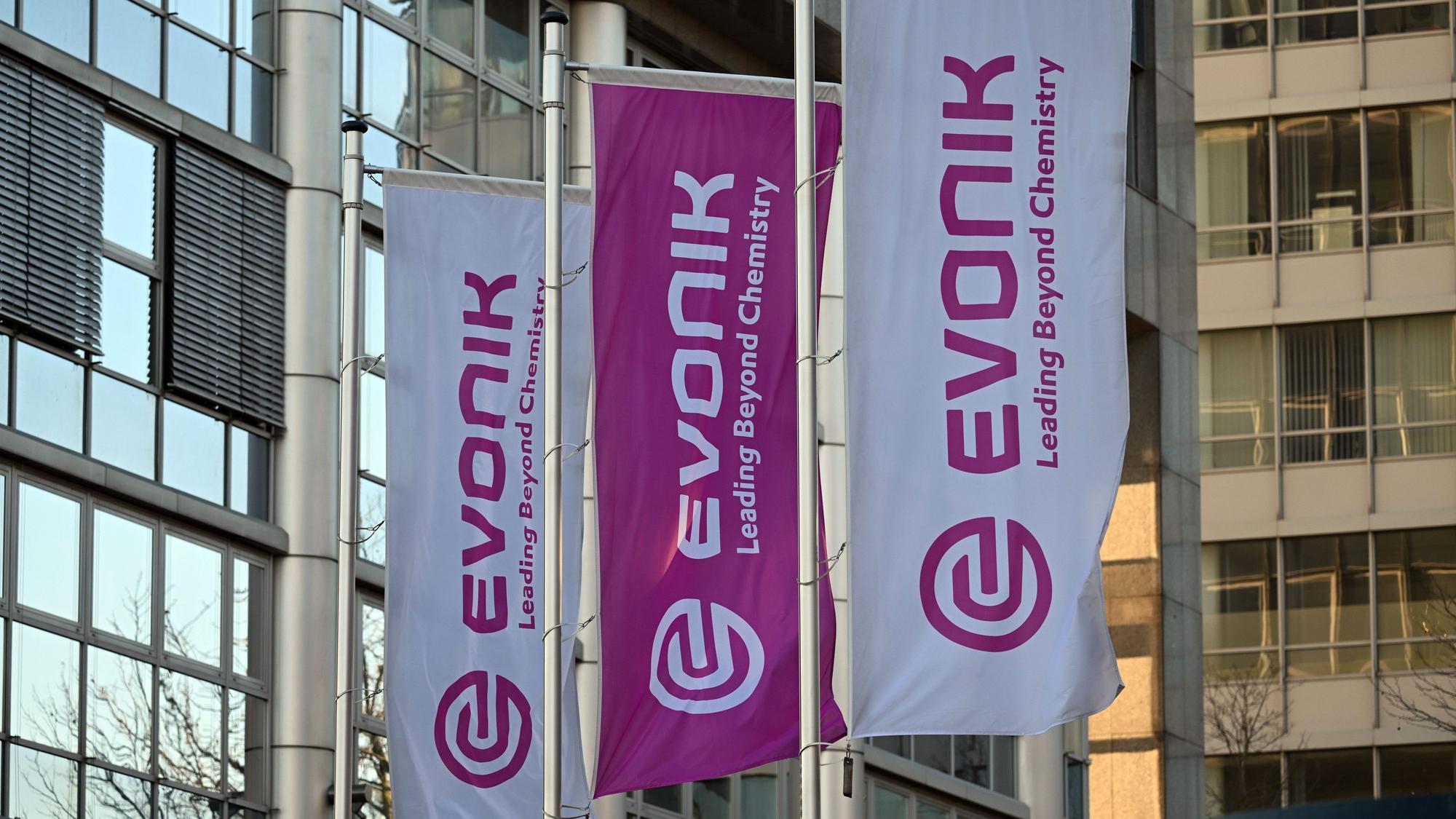 Flaggen mit dem Firmenlogo von Evonik wehen vor der Zentrale des Unternehmens.