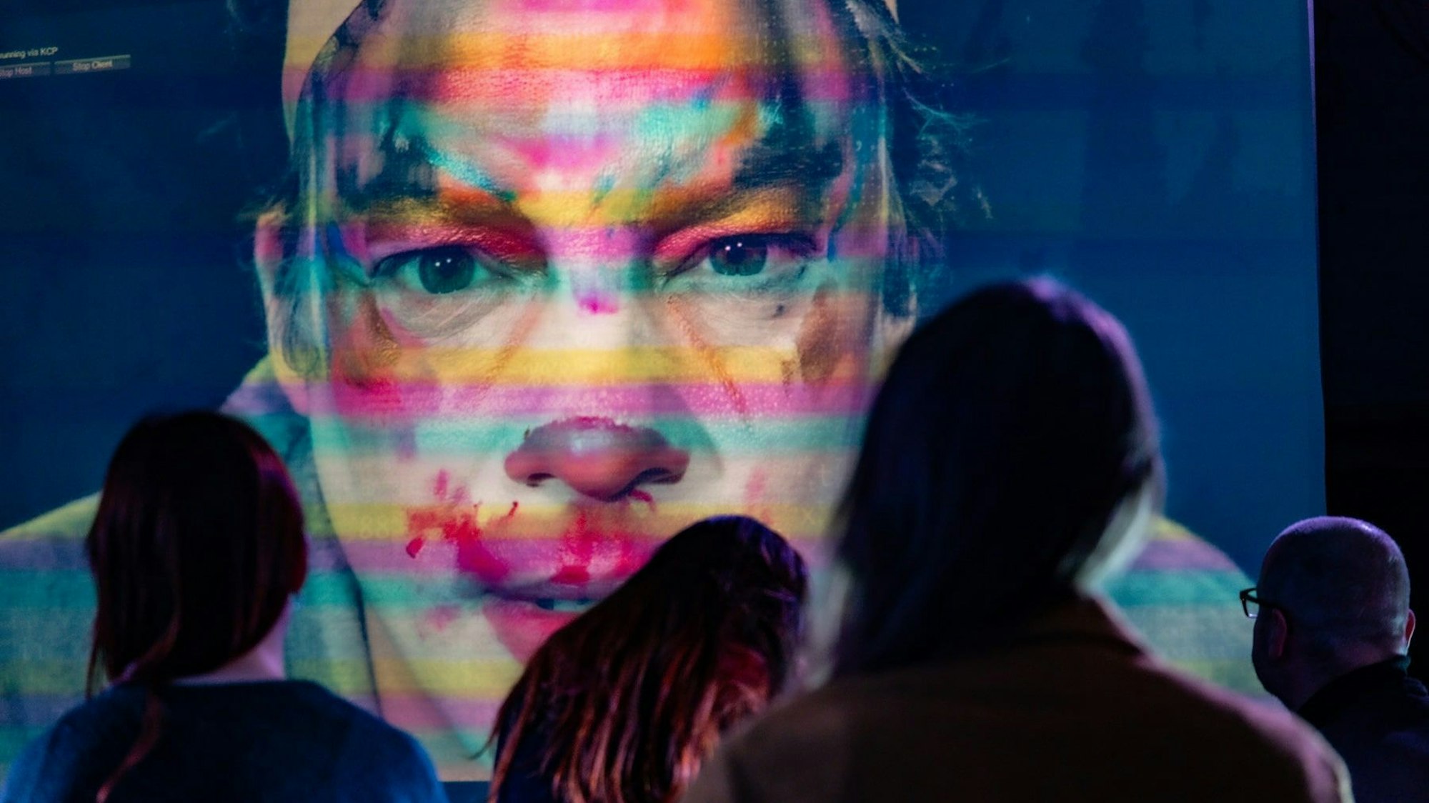 Das grotesk geschminkte Gesicht eines Clowns auf einer Videoleinwand.