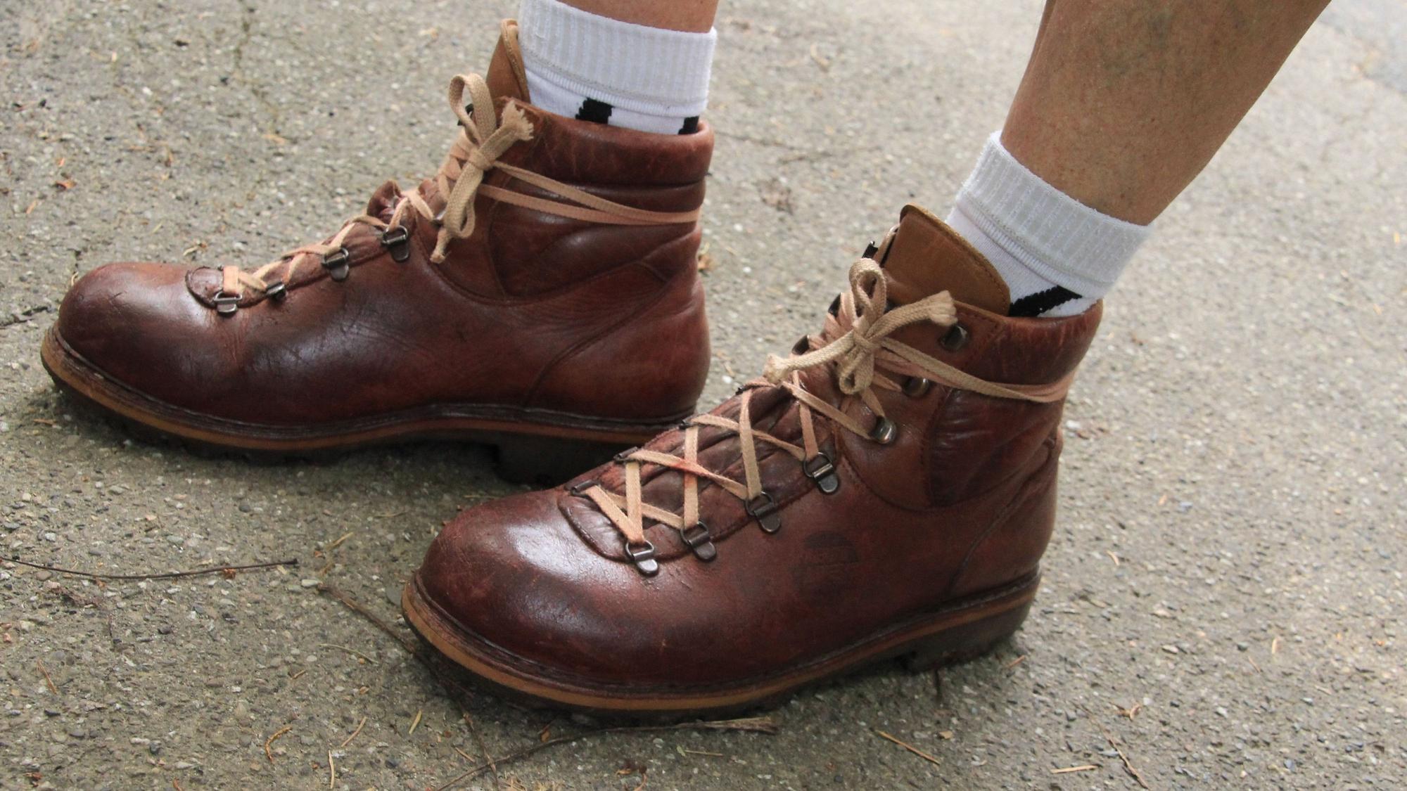 Füße mit Wanderschuhen auf einer Straße.