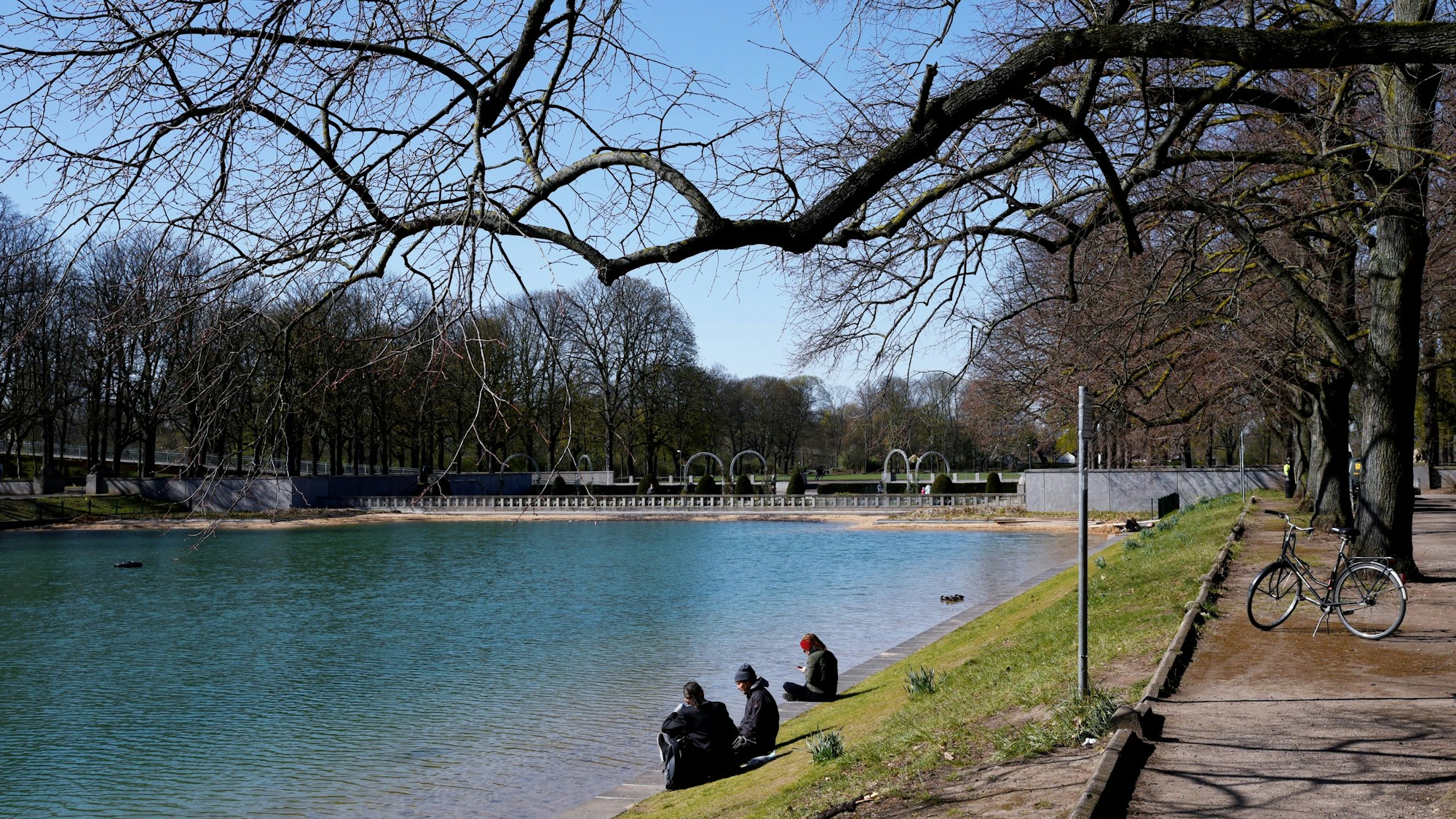 Menschen sitzen am Ufer des Weihers im Blücherpark