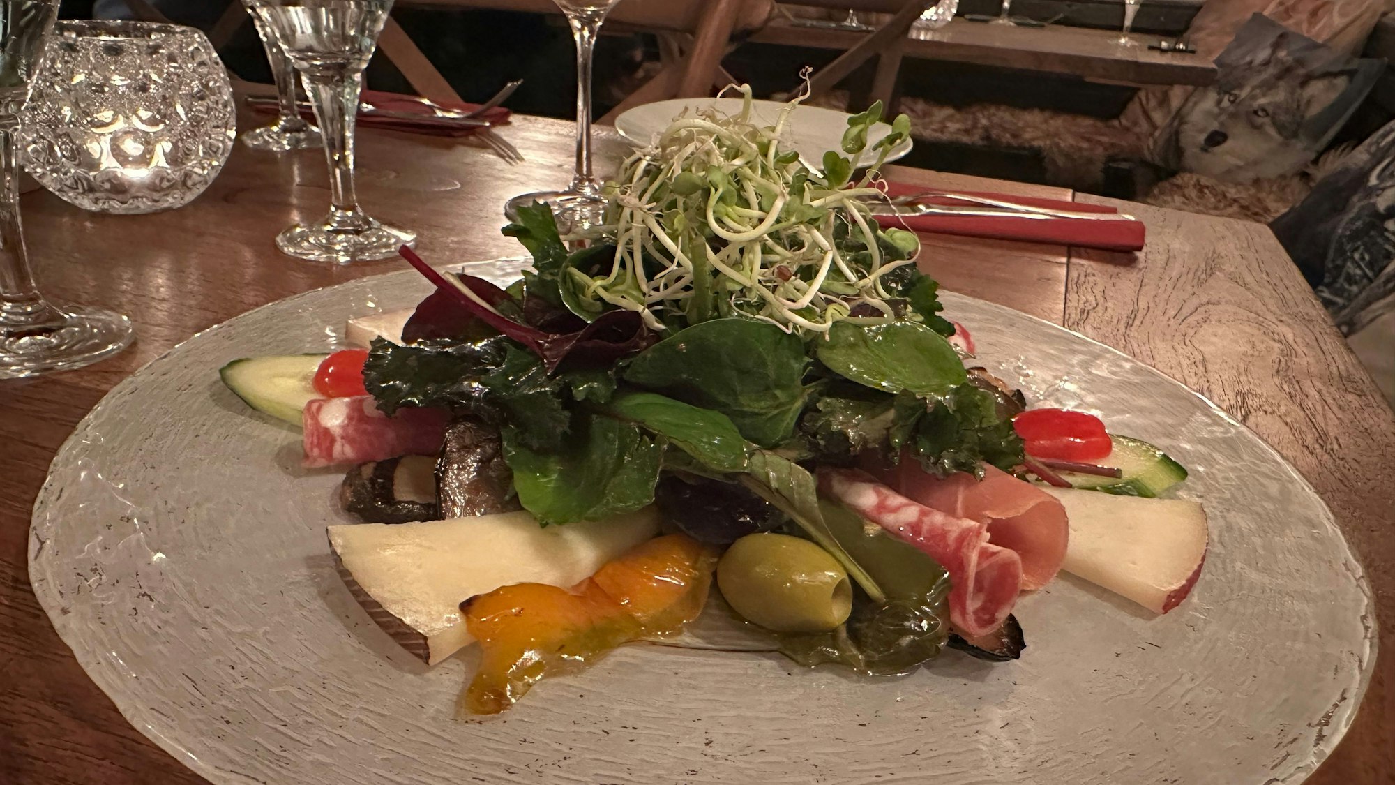 Ein Antipasti-Vorspeisenteller mit Käse, Schinken, Salat, Tomaten und Gurken.