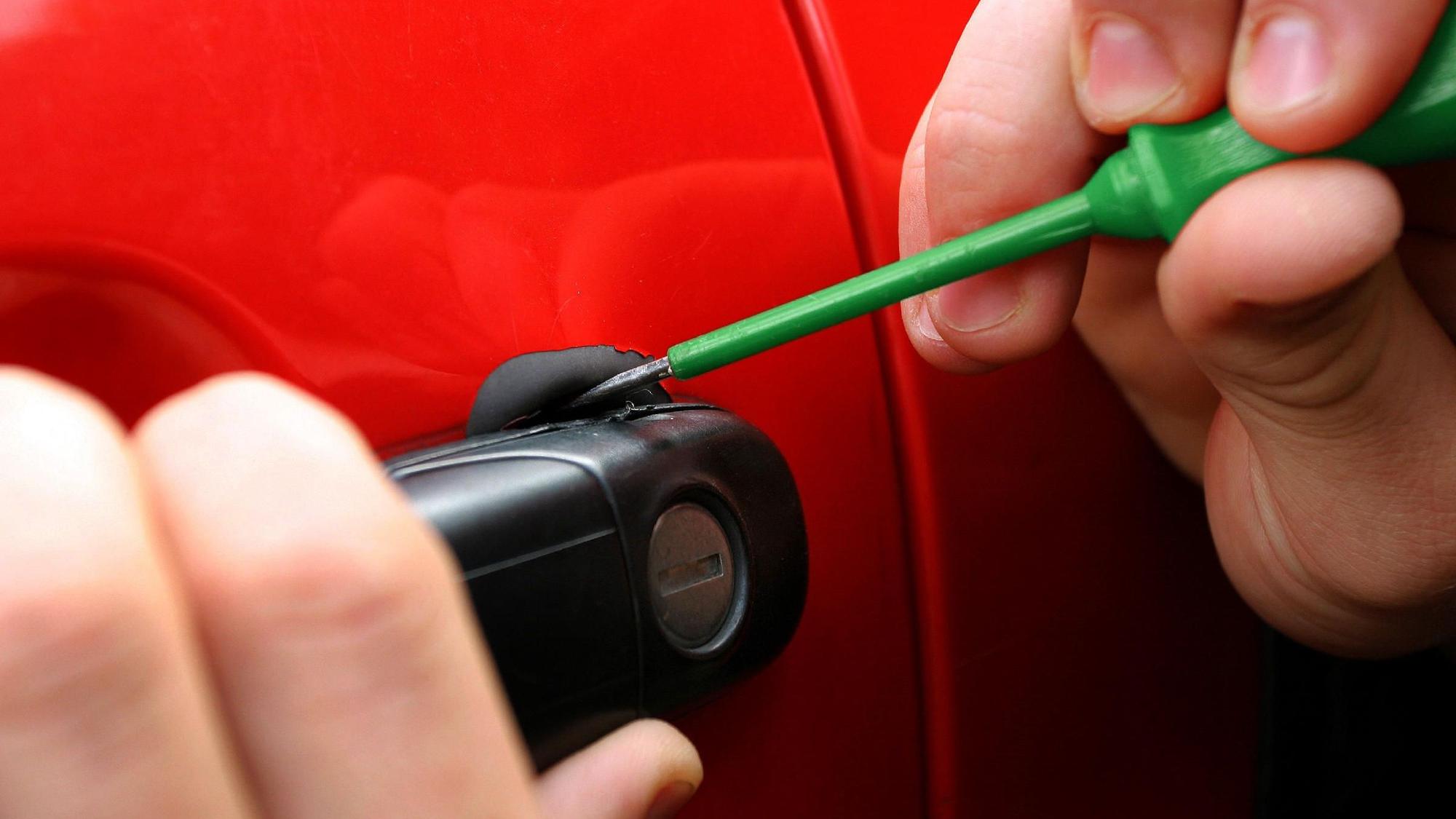 Eine Autotür wird mit Hilfe eines Schraubenziehers geöffnet.