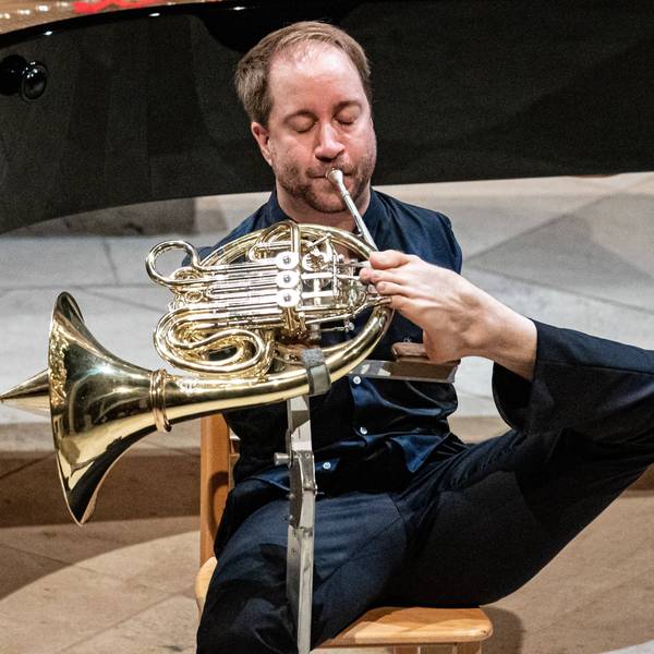 Auf dem Bild ist der Hornist Felix Klieser zu sehen, der sein Horn mit den Zehen spielt.