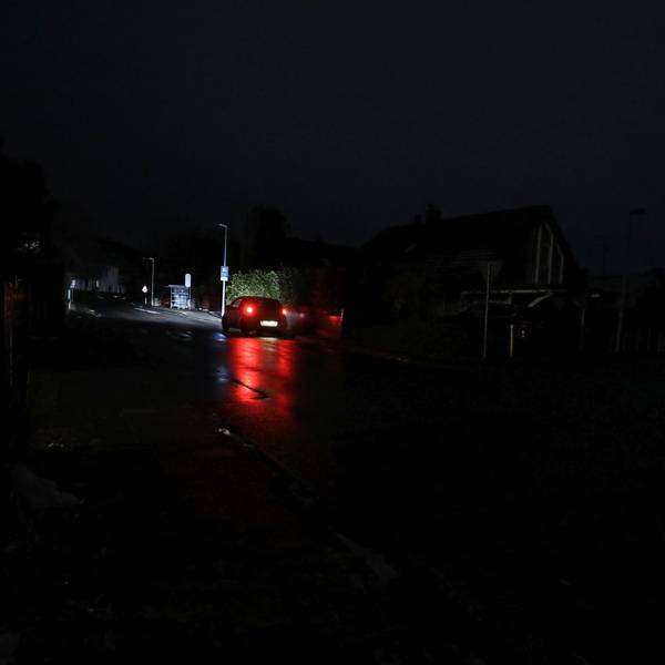 Die roten Rücklichter eines fahrenden Autos auf einer sehr dunklen Straße.
