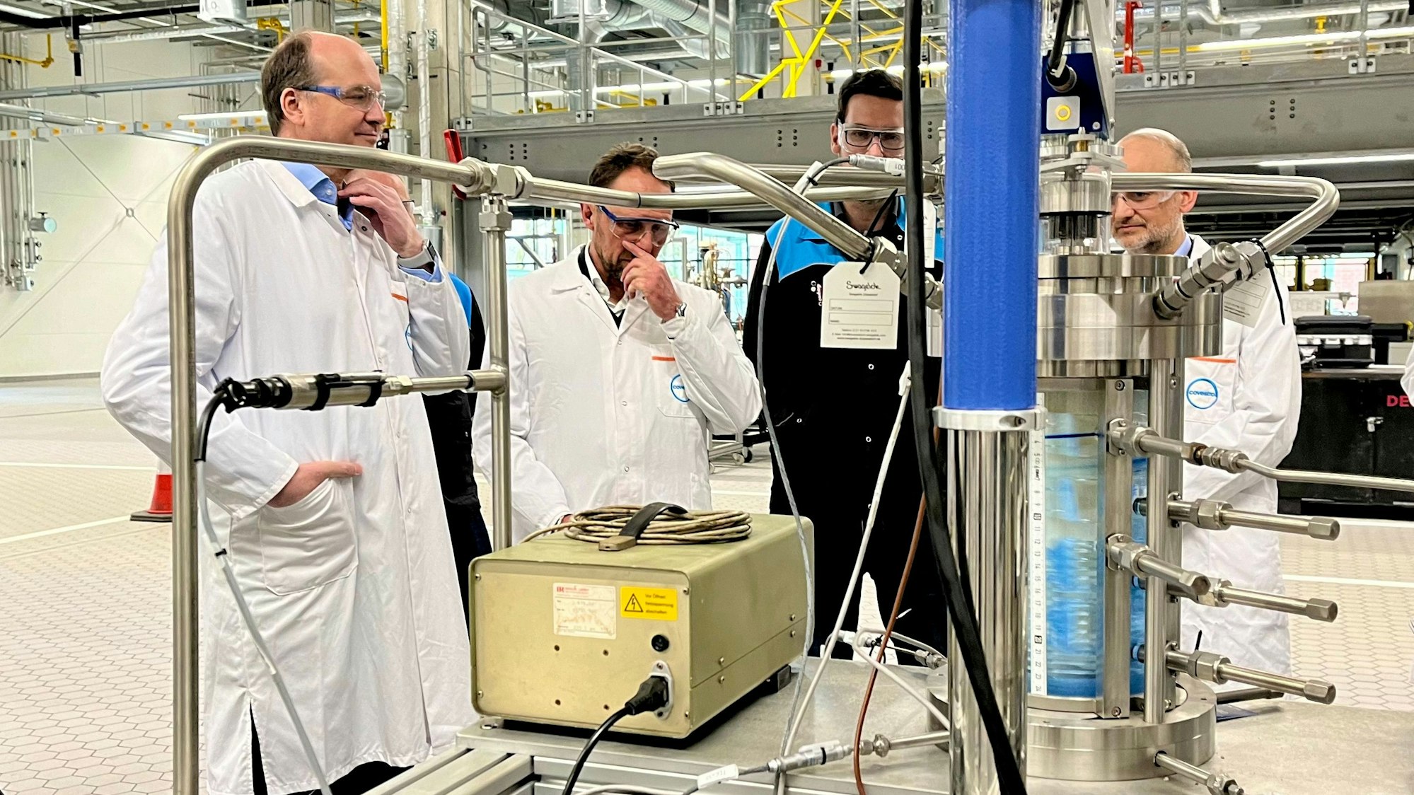 Daniel Koch, Leiter der Niederrhein-Standorte, OB Uwe Richrath (links) und Markus Dugal (rechts) lassen sich eine Covestro-Versuchsanlage von Gregor Kronenberg erklären.