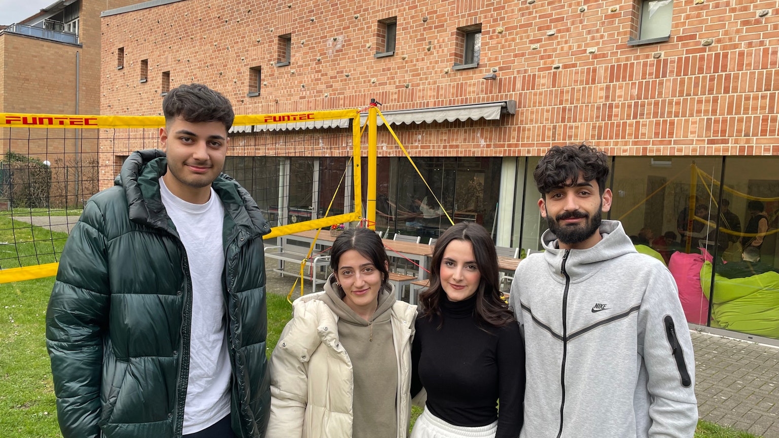 Die Besucherinnen und Besucher des Rondorfer Jugendzentrums „eins2null'“ Hamada(19), Sedra (20), Janaman (17) und Hadi (22) (von links) stehen vor dem Gebäude mit großen Glasfassaden.