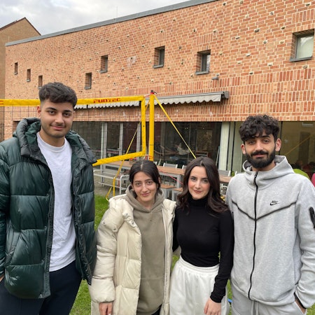 Die Besucherinnen und Besucher des Rondorfer Jugendzentrums „eins2null'“ Hamada(19), Sedra (20), Janaman (17) und Hadi (22) (von links) stehen vor dem Gebäude mit großen Glasfassaden.