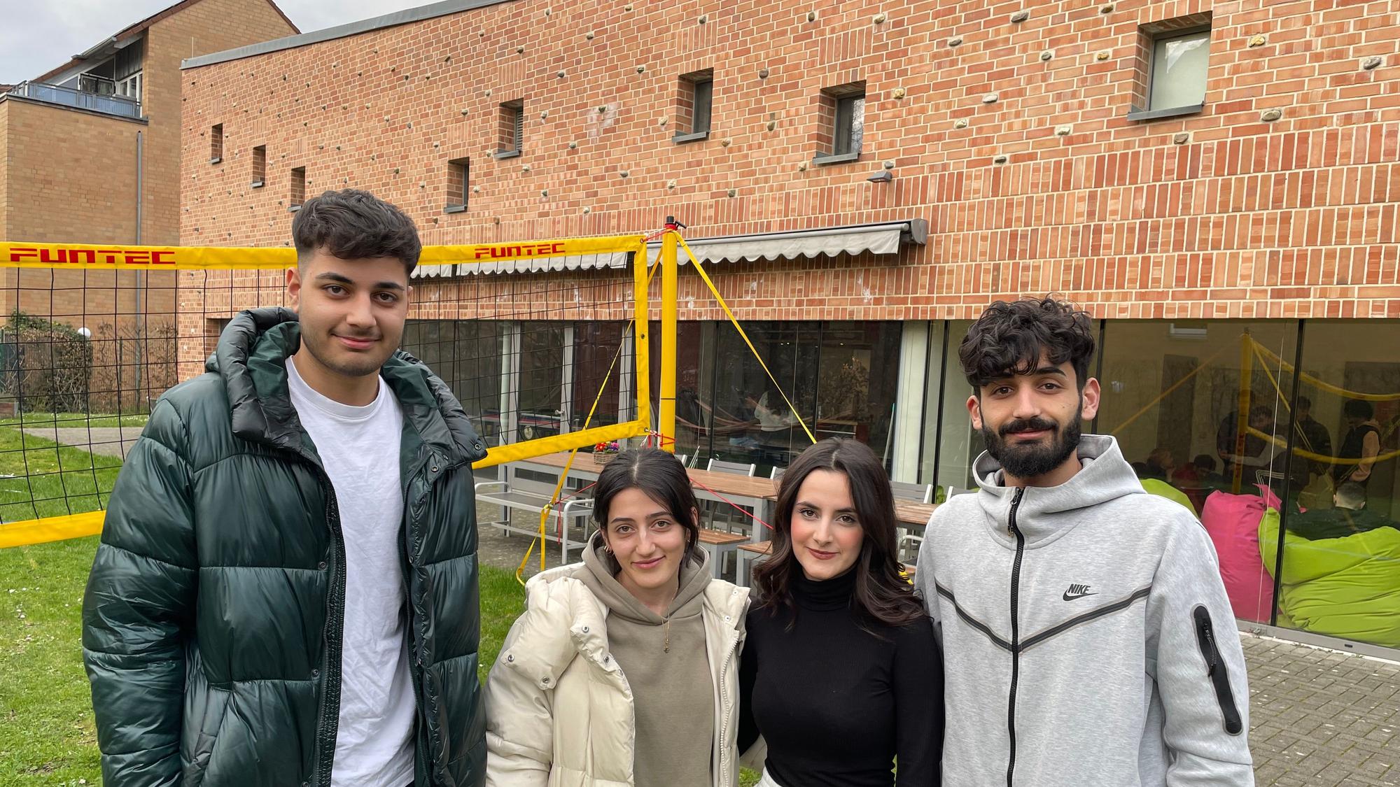 Die Besucherinnen und Besucher des Rondorfer Jugendzentrums „eins2null'“ Hamada(19), Sedra (20), Janaman (17) und Hadi (22) (von links) stehen vor dem Gebäude mit großen Glasfassaden.