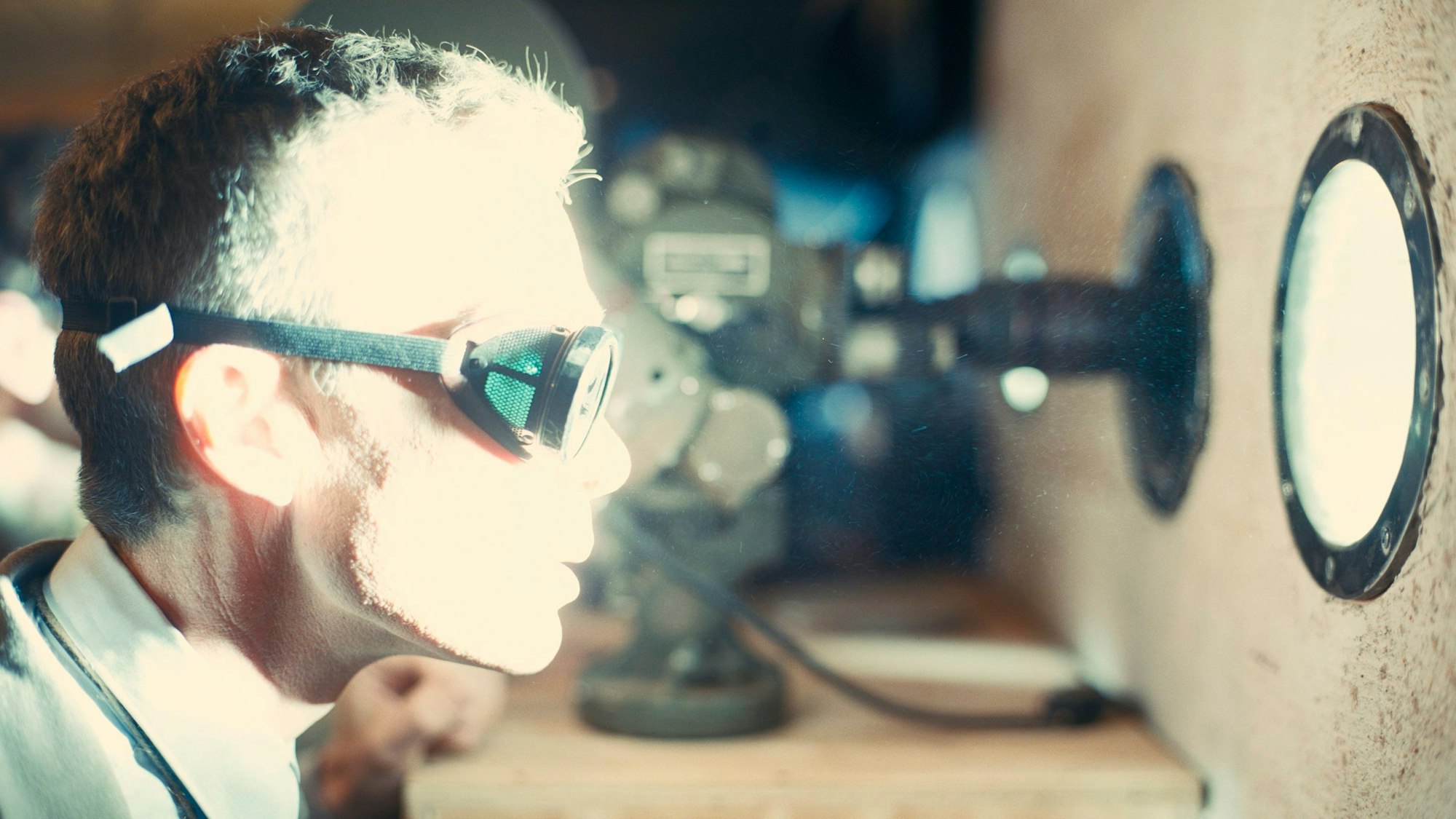 Ein Mann schaut durch ein kleines Fenster in gleißendes Licht.