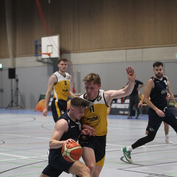 Jan Züll hält mit dem linken Arm einen Gegner von sich fern, mit dem rechten führt er den Ball.