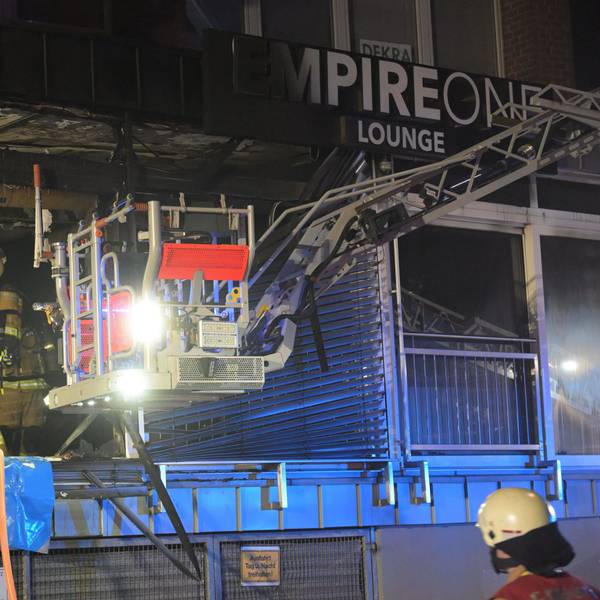 Feuerwehrleute arbeiten in einem ausgebrannten Ladenlokal.