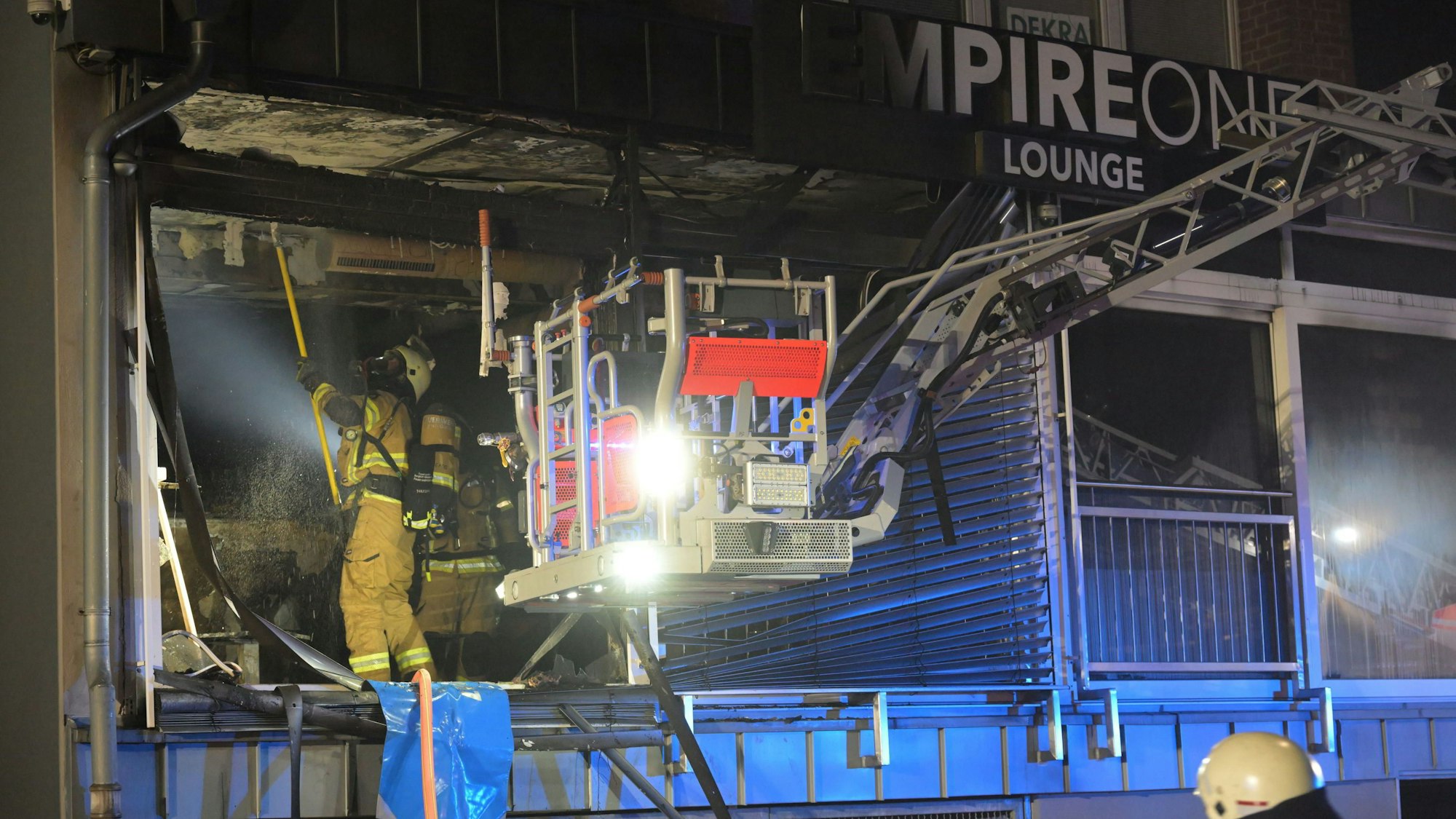 Feuerwehrleute arbeiten in einem ausgebrannten Ladenlokal.