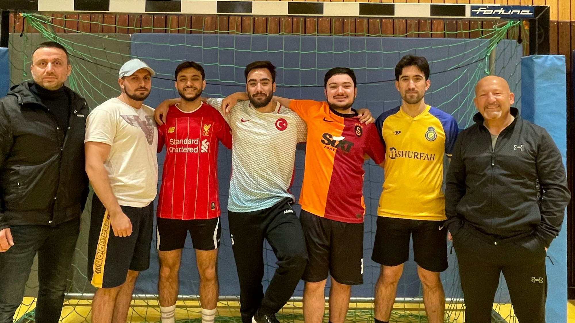 Fünf Teilnehmer des Mitternachtsfußballs stehen mit ihren beiden Betreuern im Fußballtor.