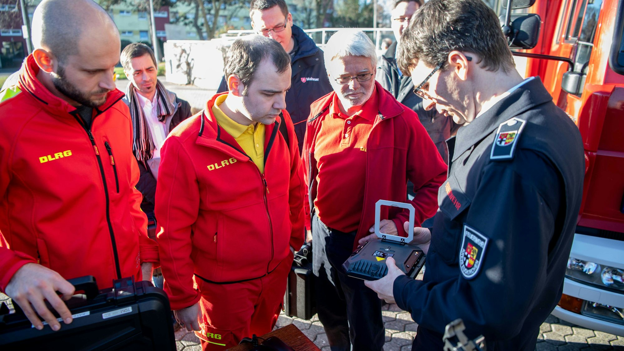 Das Bild zeigt drei Vertreter der DLRG, die sich das Satellitentelefon erklären lassen.