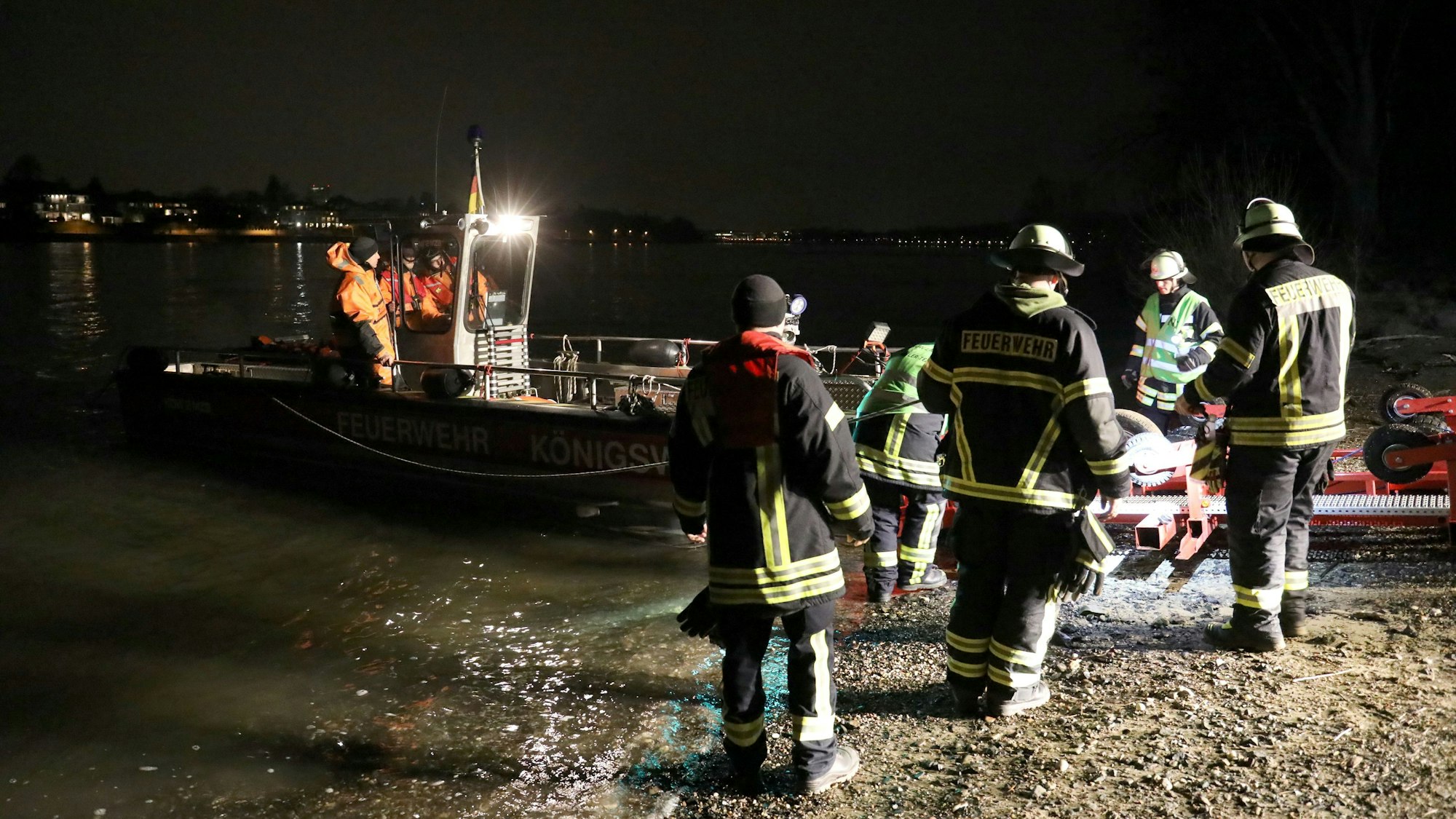 Feuerwehrleute helfen nachts bei der Rettung einer Frau aus dem Rhein in Bonn.