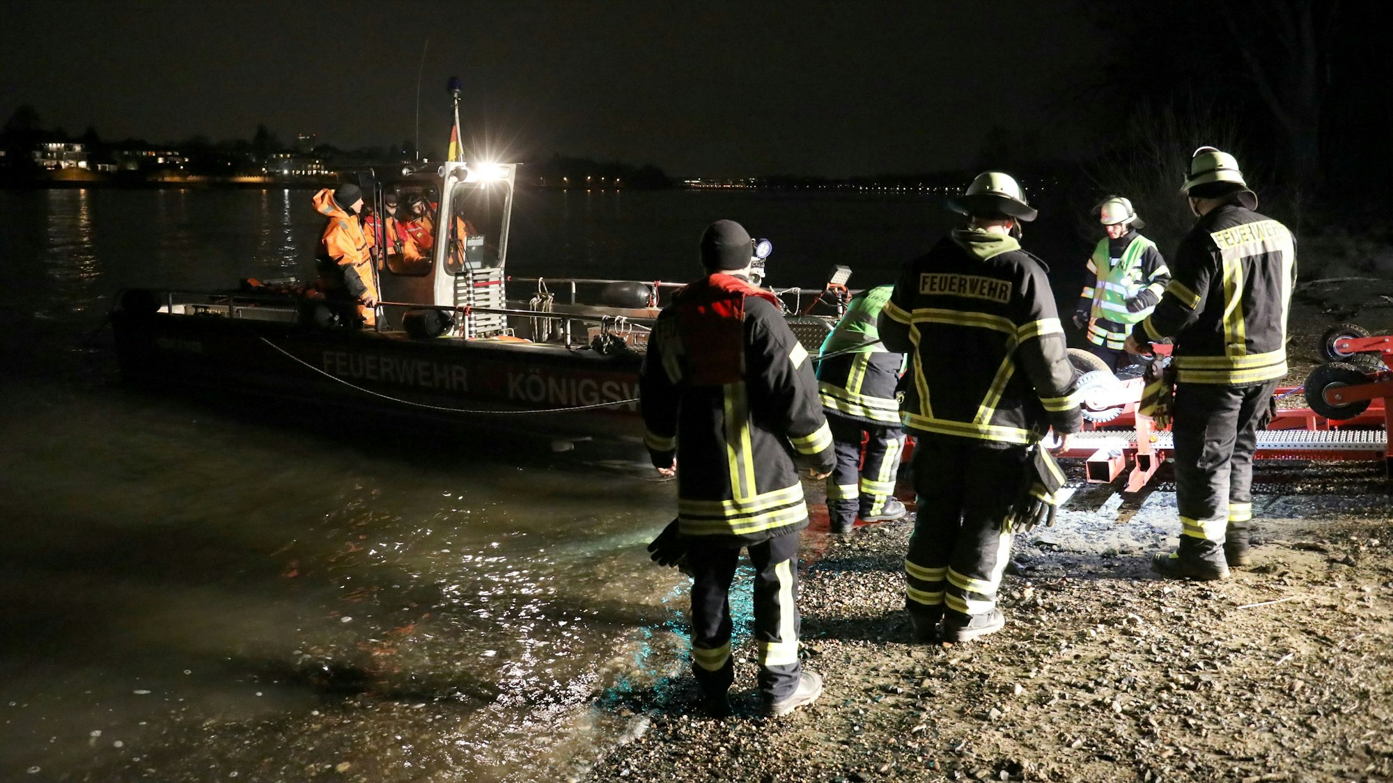 Einsatzkräfte bei Nacht am Rhein mit einem Rettungsboot