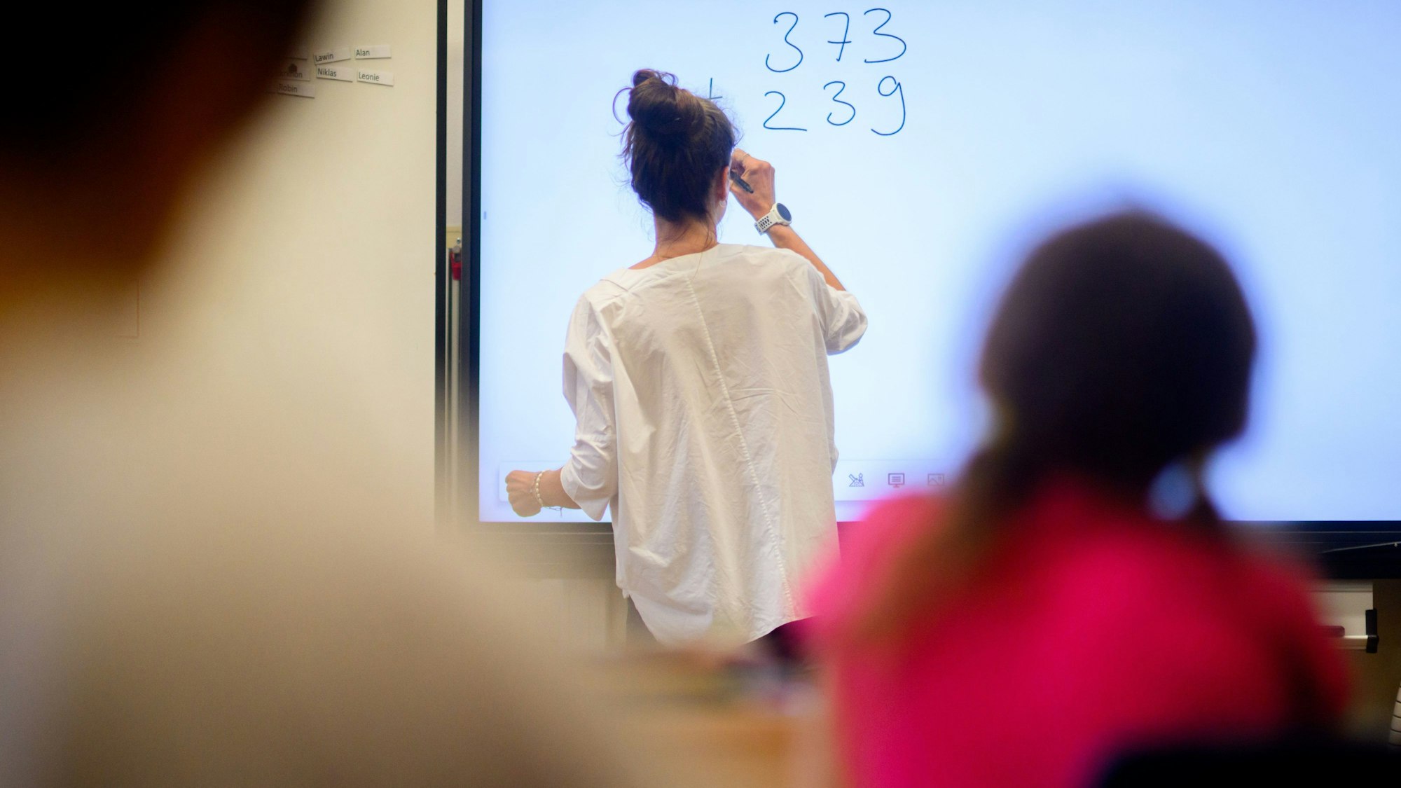 Eine Lehrerin schreibt an eine digitale Tafel.