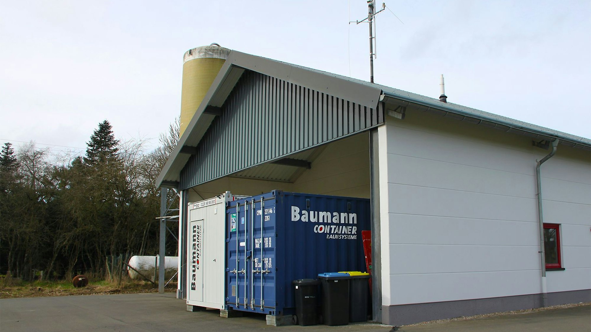 Das Bild zeigt das Feuerwehrgerätehaus. Dahinter stehen zwei Container.