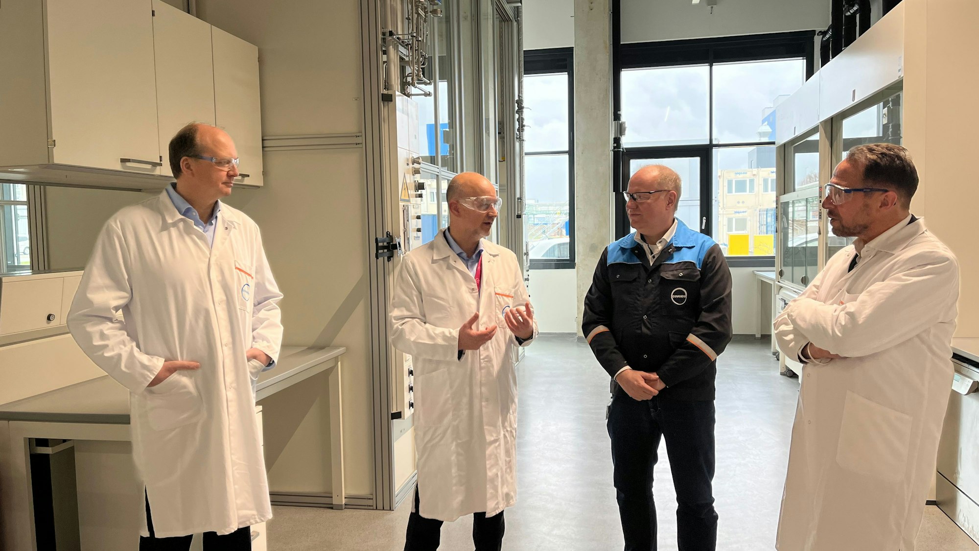 Daniel Koch, Markus Dugal und Michael Traving von Covestro stehen mit OB Uwe Richrath im neuen Covestro-Technikum.