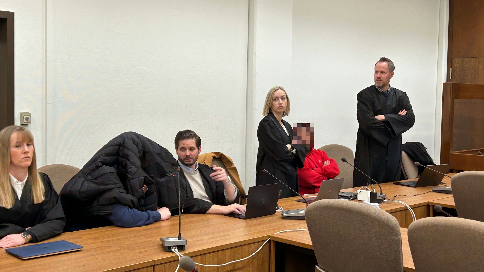 Zu sehen sind sechs Menschen in einem Gerichtssaal.
