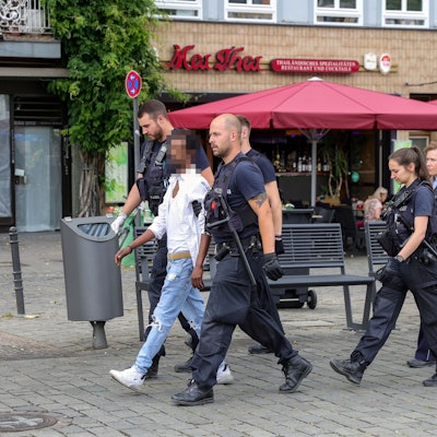 Polizisten führen einen mutmaßlichen Handydieb auf dem Kölner Heumarkt ab.