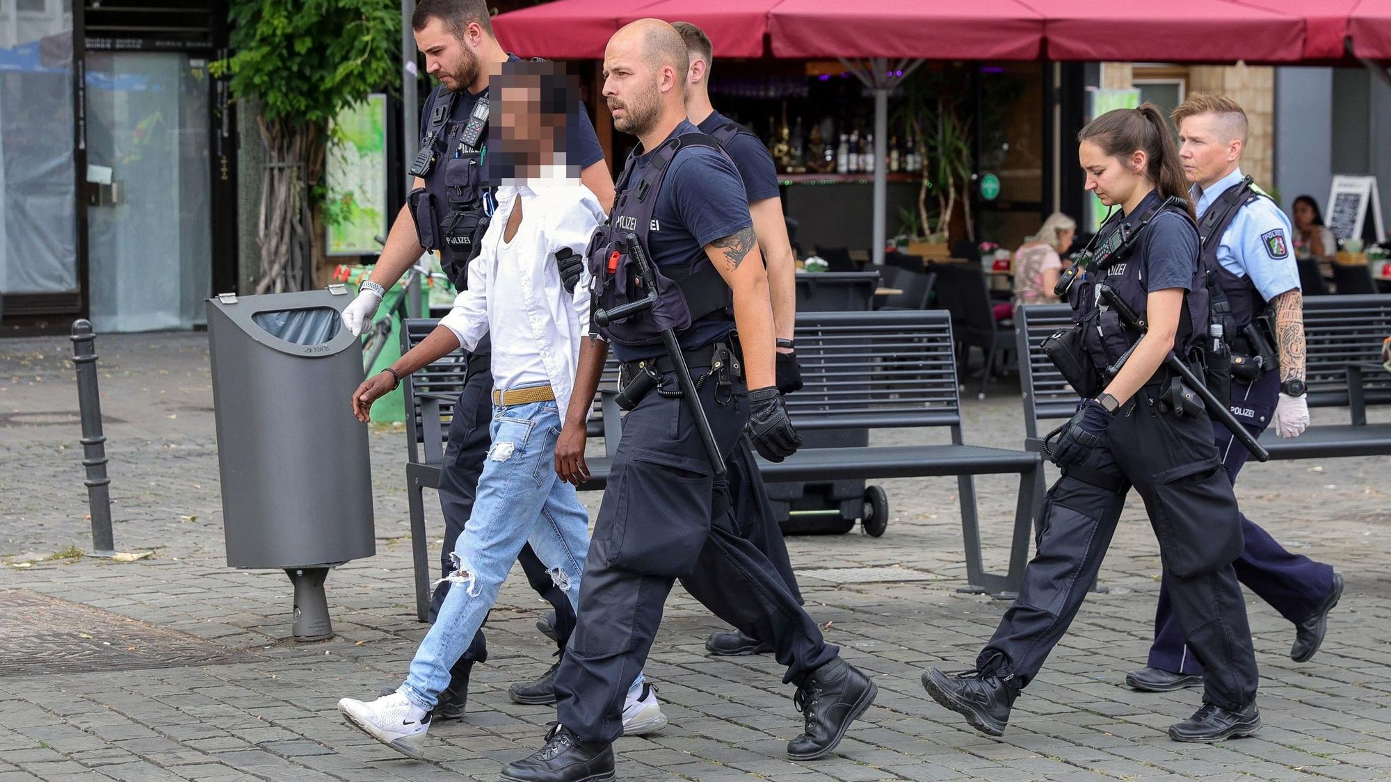 Polizisten führen einen mutmaßlichen Handydieb auf dem Kölner Heumarkt ab.