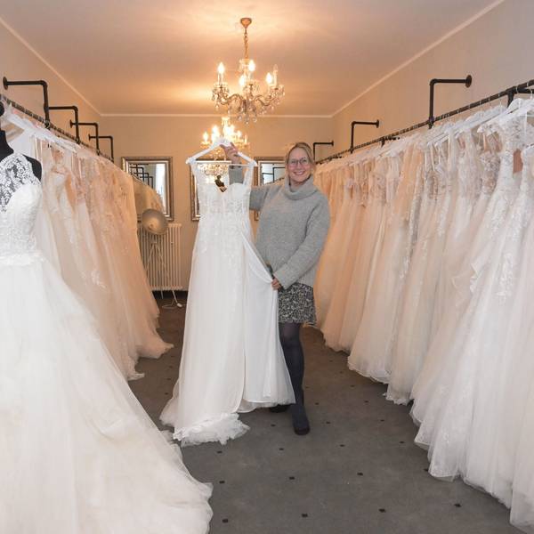 Carolin Amerling hält ein Hochzeitskleid in die Kamera.