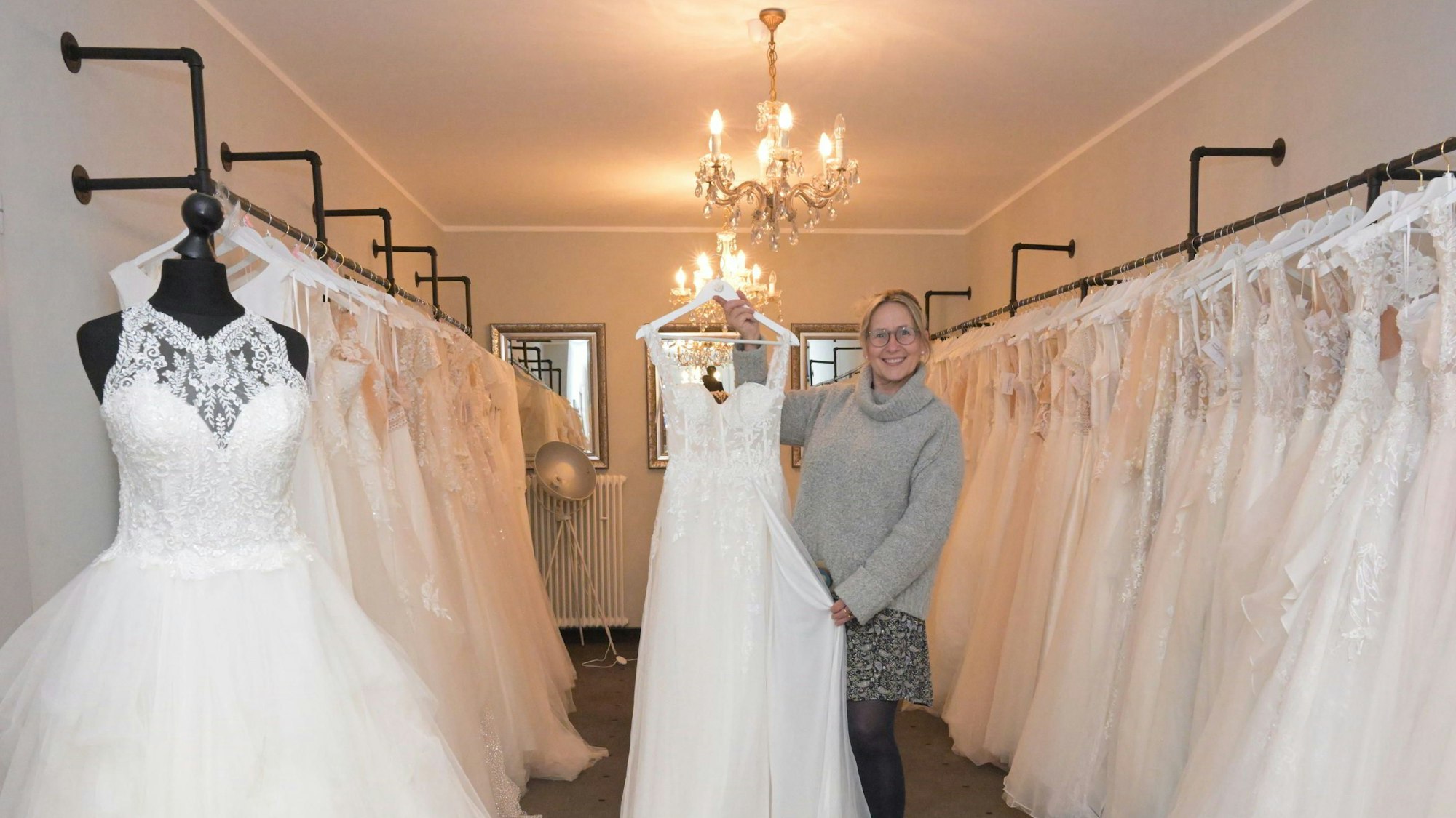 Carolin Amerling hält ein Hochzeitskleid in die Kamera.