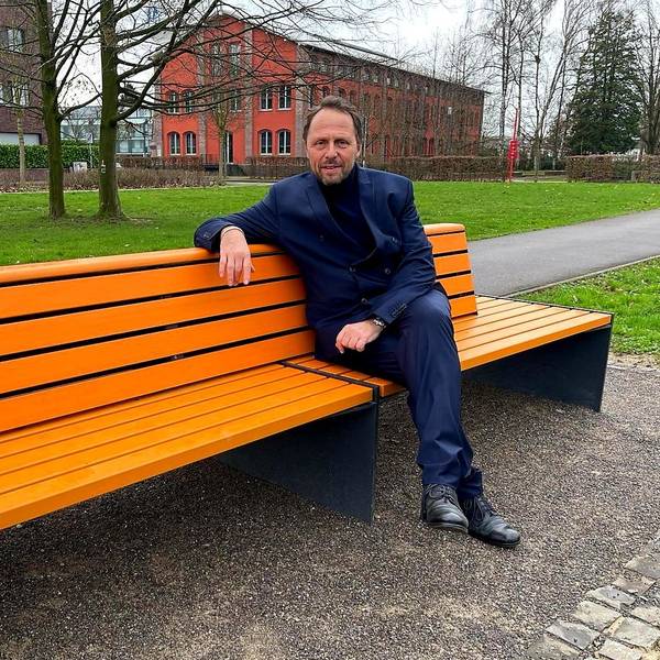 Der Leverkusener OB (Oberbürgermeister) Uwe Richrat (SPD) sitzt auf der vom Zonta-Club Leverkusen aufgestellten orangenen Bank in der Neuen Bahnstadt Opladen, auf der Susanne Wedewer ihn (und demnächst andere bekannte Menschen der Stadt) zum Thema Frauenrechte, Gleichstellung, Sexismus, Gewalt gegen Frauen befragte.