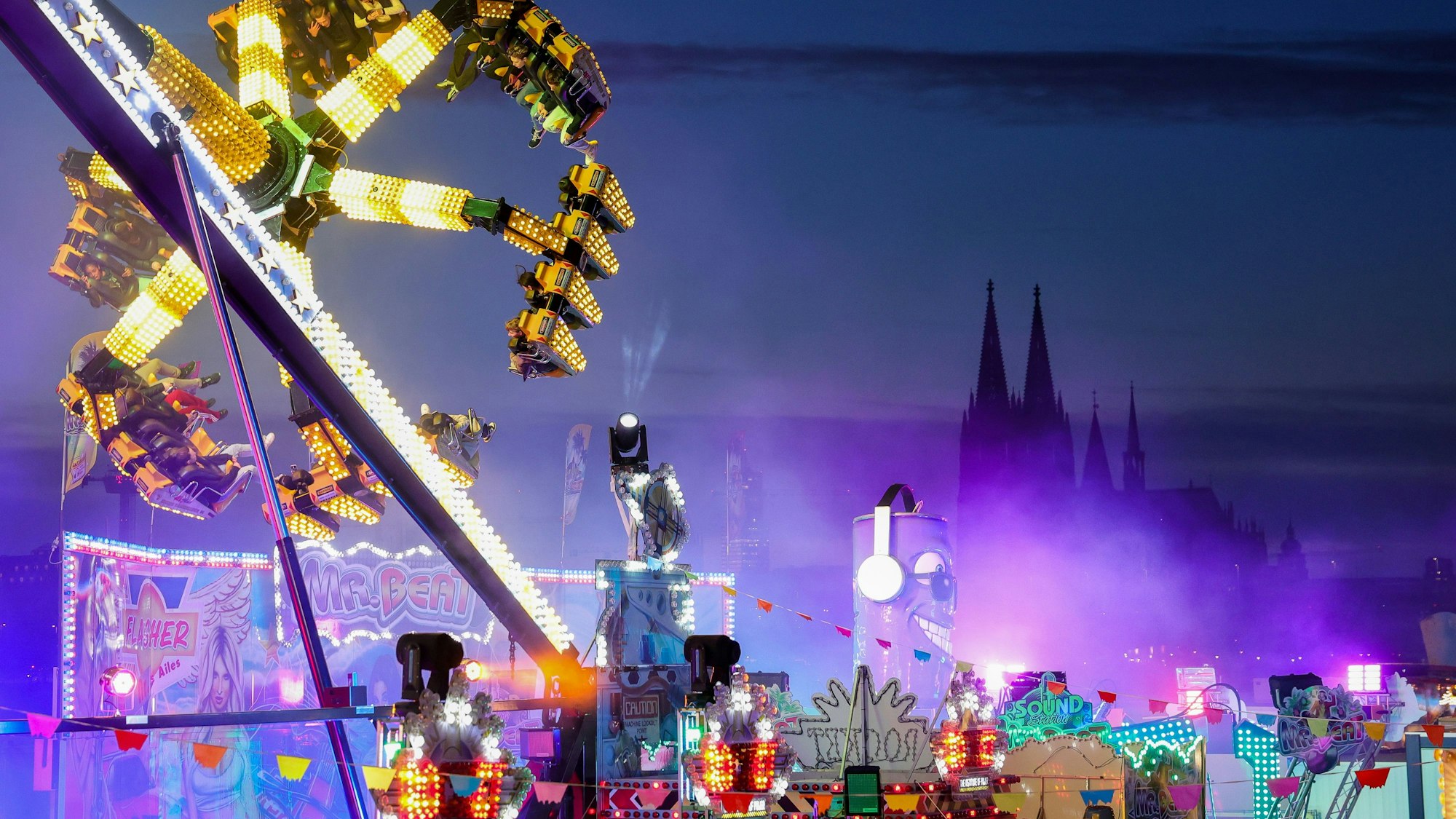 Fahrgeschäfte auf der Deutzer Kirmes im Abendlicht.