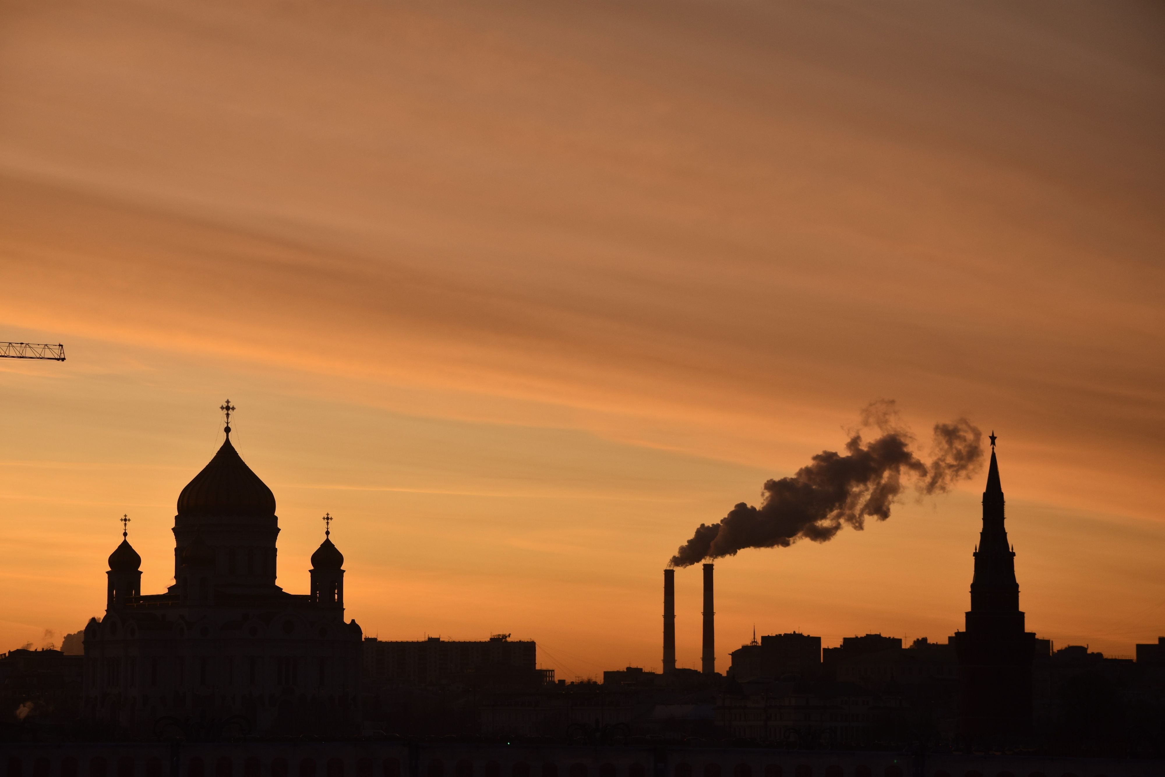 In der russischen Hauptstadt sind die Silhouetten der Christ-Erlöser-Kathedrale, eines Kraftwerks und des Kremls in der Abenddämmerung zu sehen.