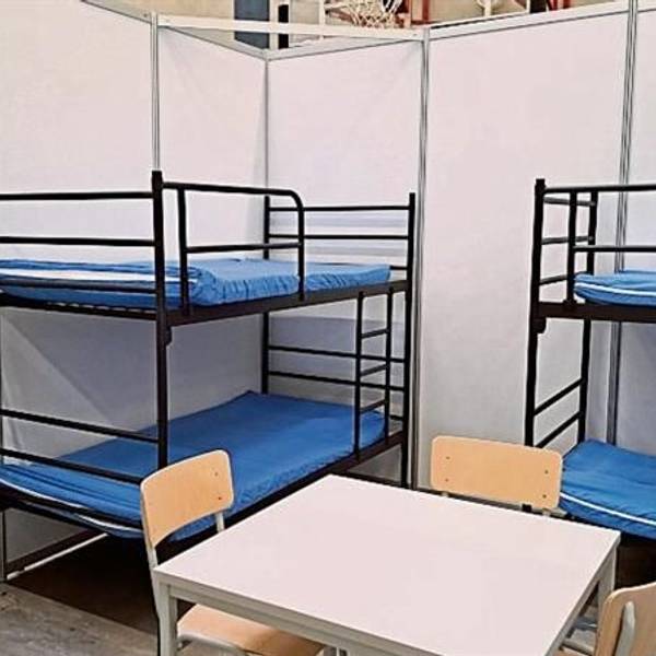 Rund zwei Meter hohe Wände schirmen zwei Etagenbetten, einen Tisch mit Stühlen und einen Schrank ab.