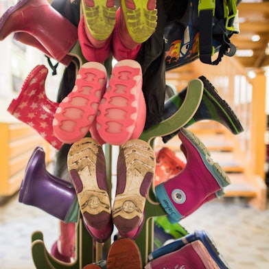 Gummistiefel für Kinder sind an einer Garderobe in einer Kindertagesstätte zu sehen.