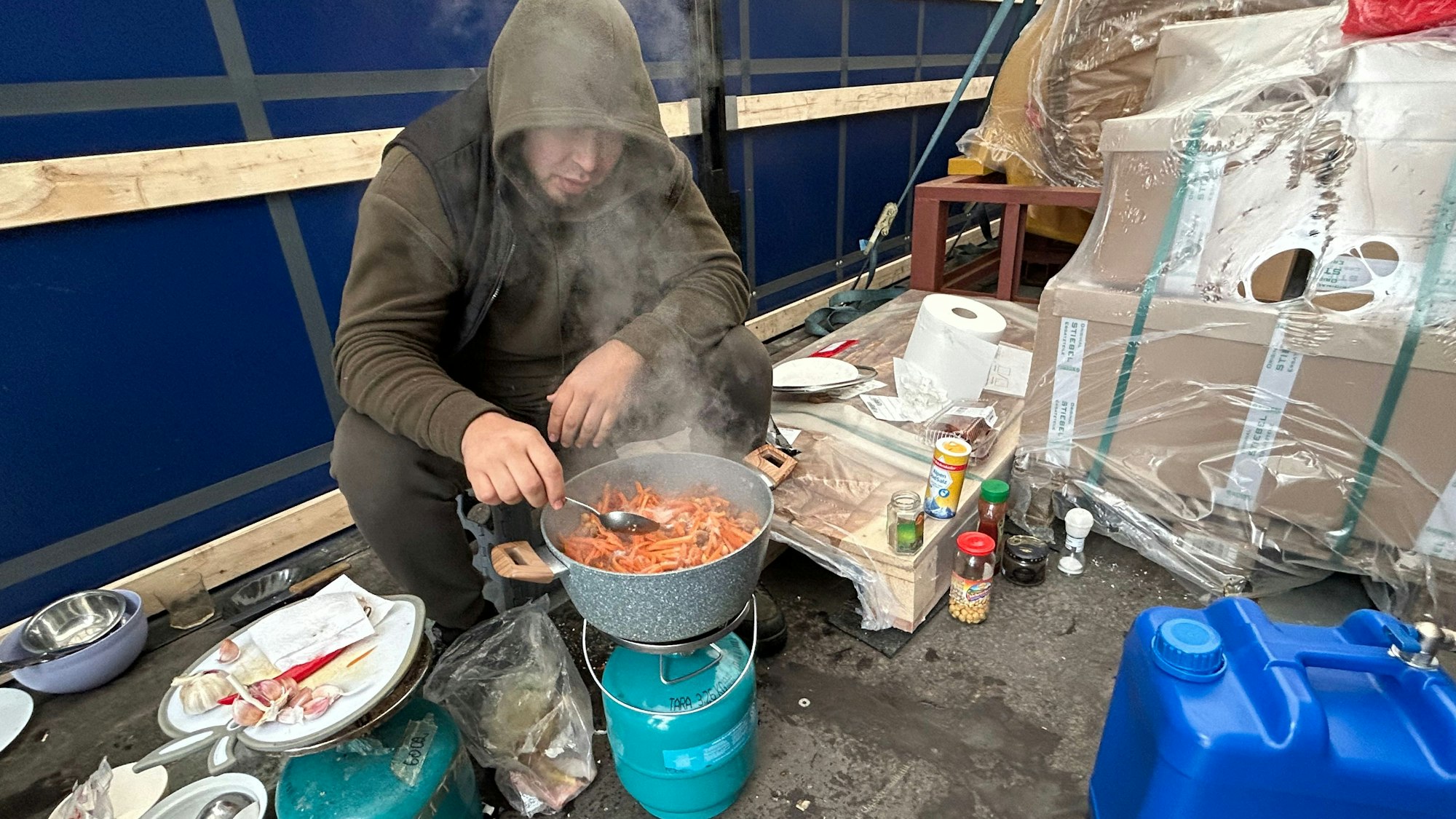 Ein Fahrer aus Tadschikistan kocht eine Suppe im Auflieger seines Lkw.