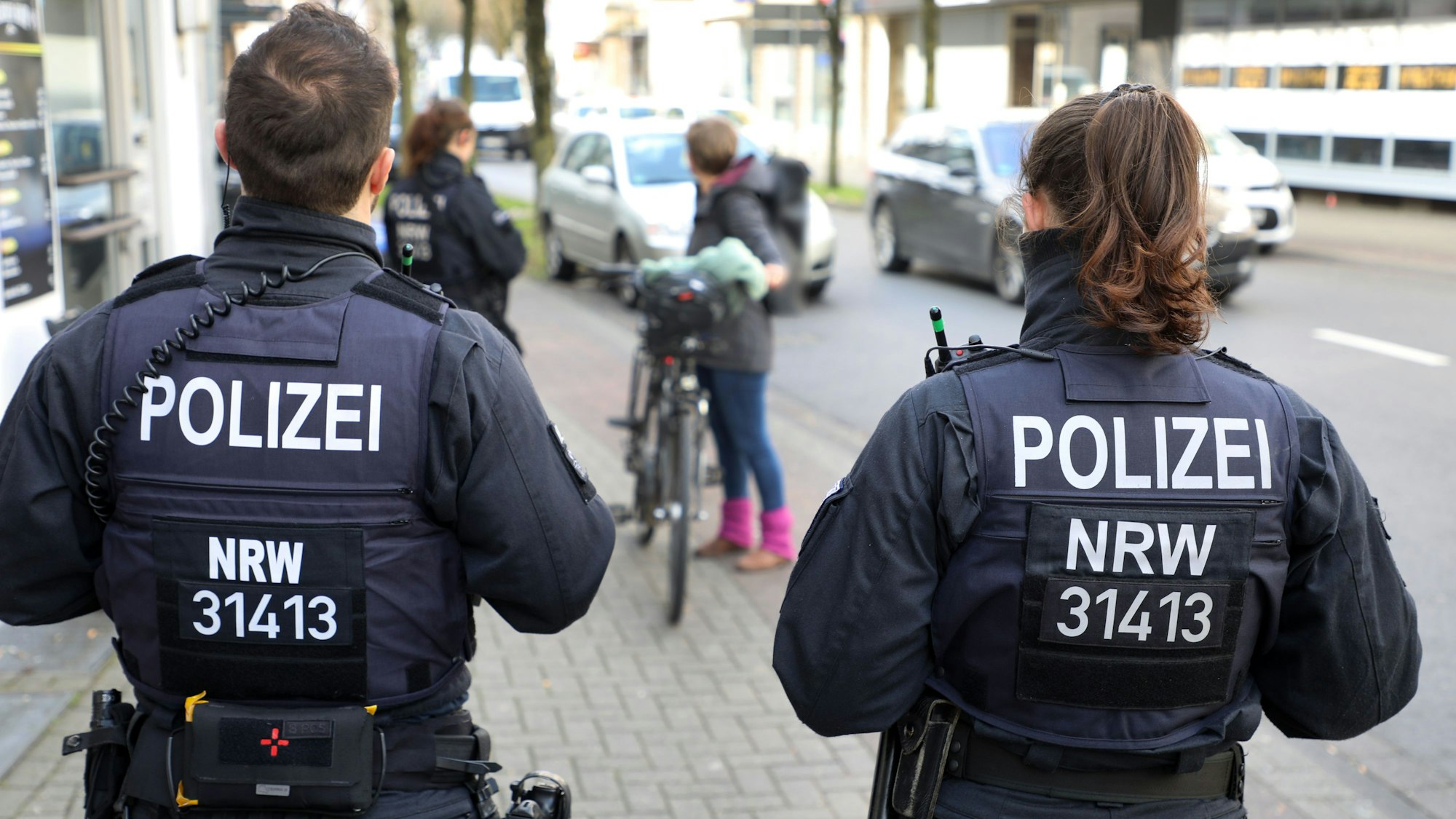 Polizeibeamte und -beamtinnen der Bereitschaftspolizei kontrollieren eine Fahrradfahrerin in Bergisch Gladbach.
