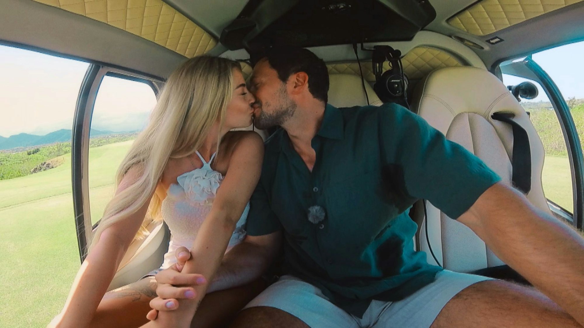 Eine Frau und eine Mann küssen sich in einem Helikopter.