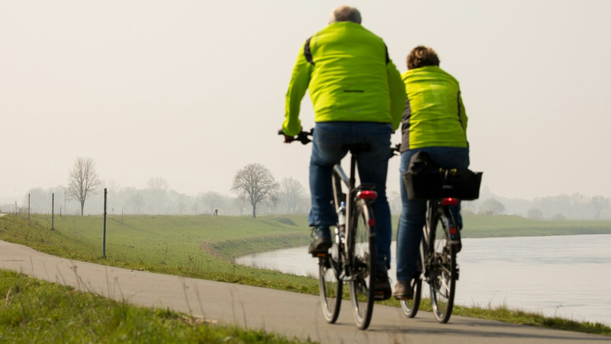 Ein Fahrradfahrer und eine Fahrradfahrerin sind auf einem Radweg unterwegs.