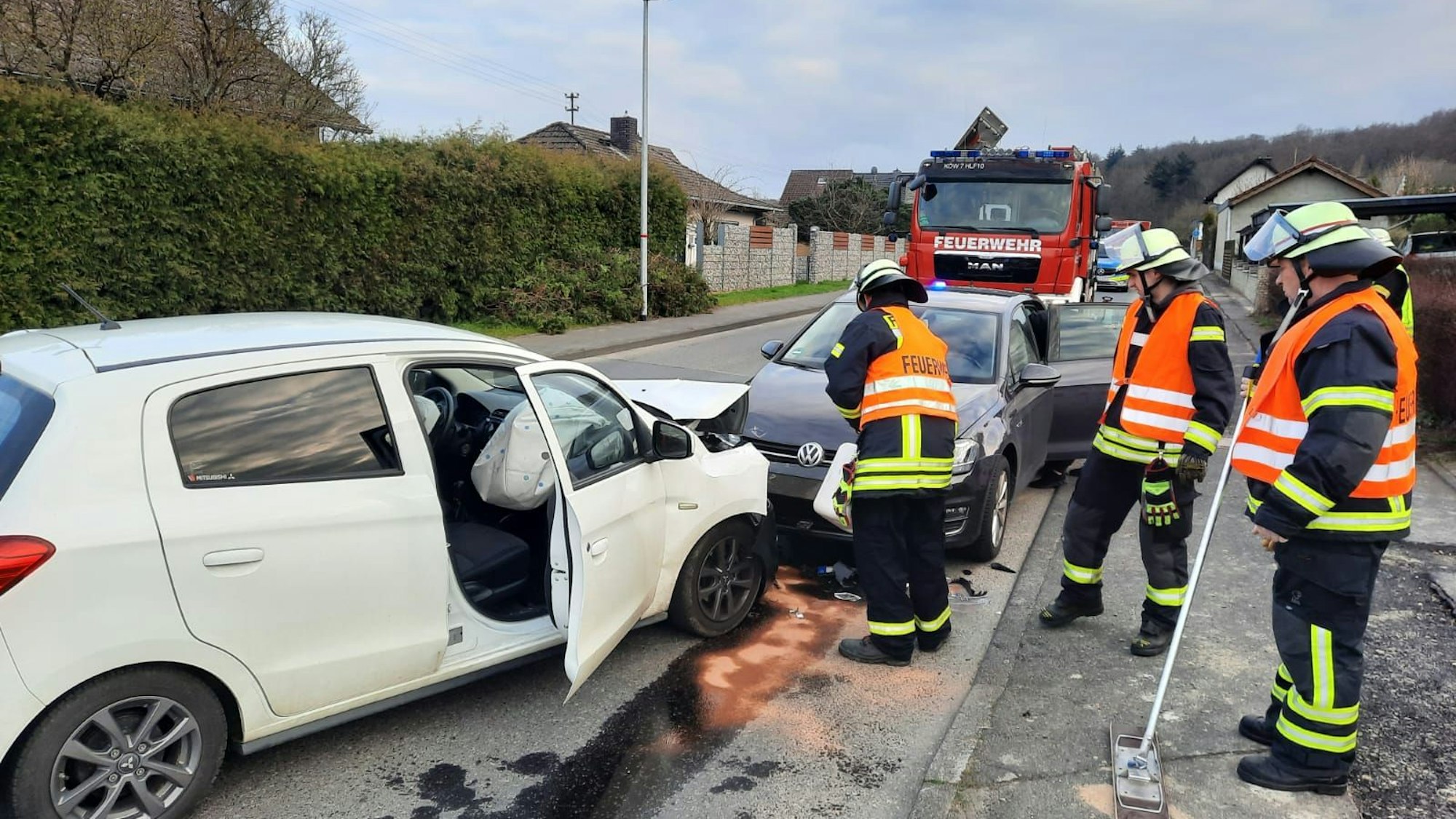 Feuerwehrleute stehen neben zwei durch den Unfall beschädigten Fahrzeugen.