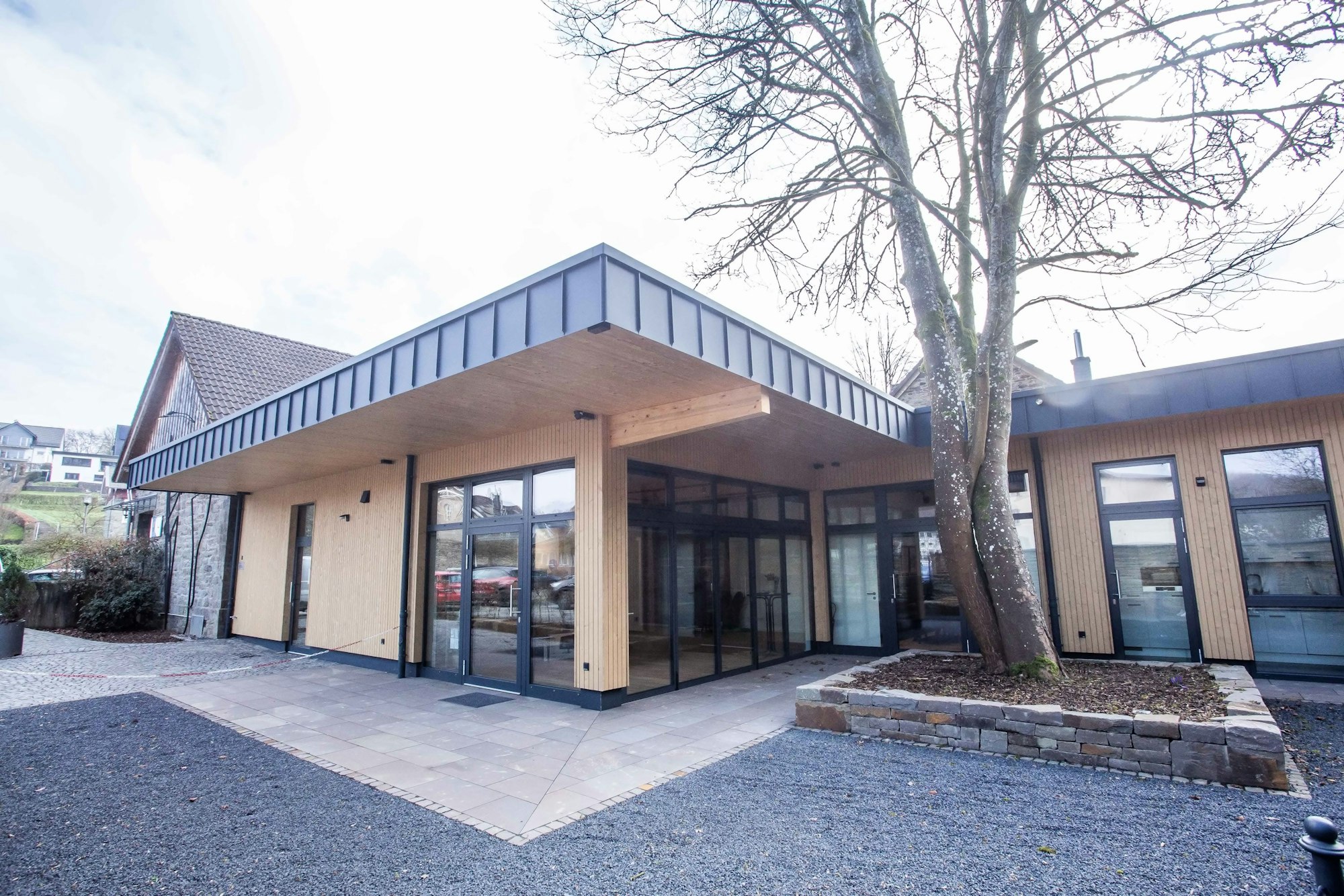 Ein modernes Gebäude mit großen Fenstern und Flachdach wurde an die historische Schlosserei von Ermen und Engels angebaut.