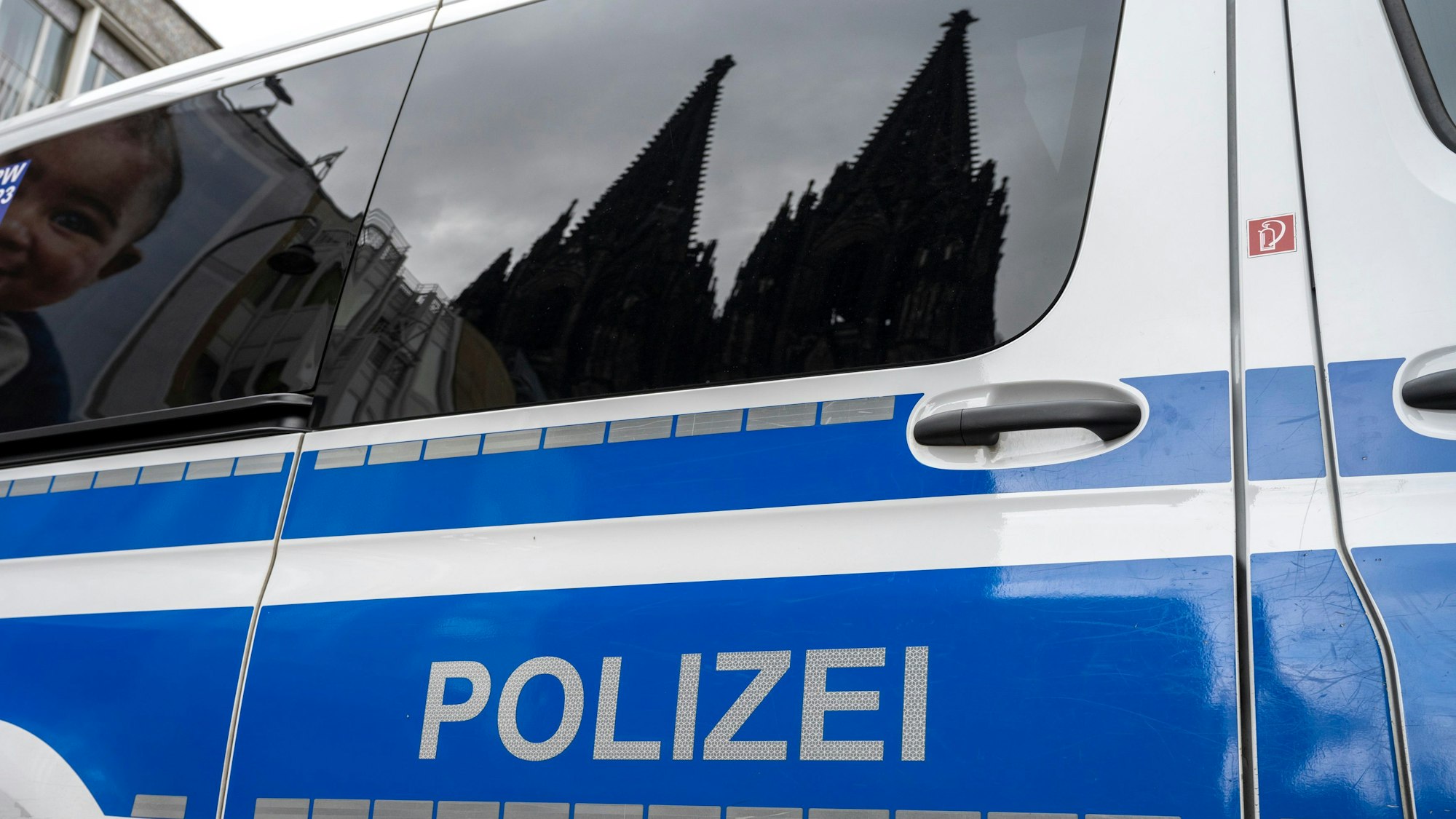 Der Kölner Dom spiegelt sich in den Scheiben eines Polizeifahrzeugs.