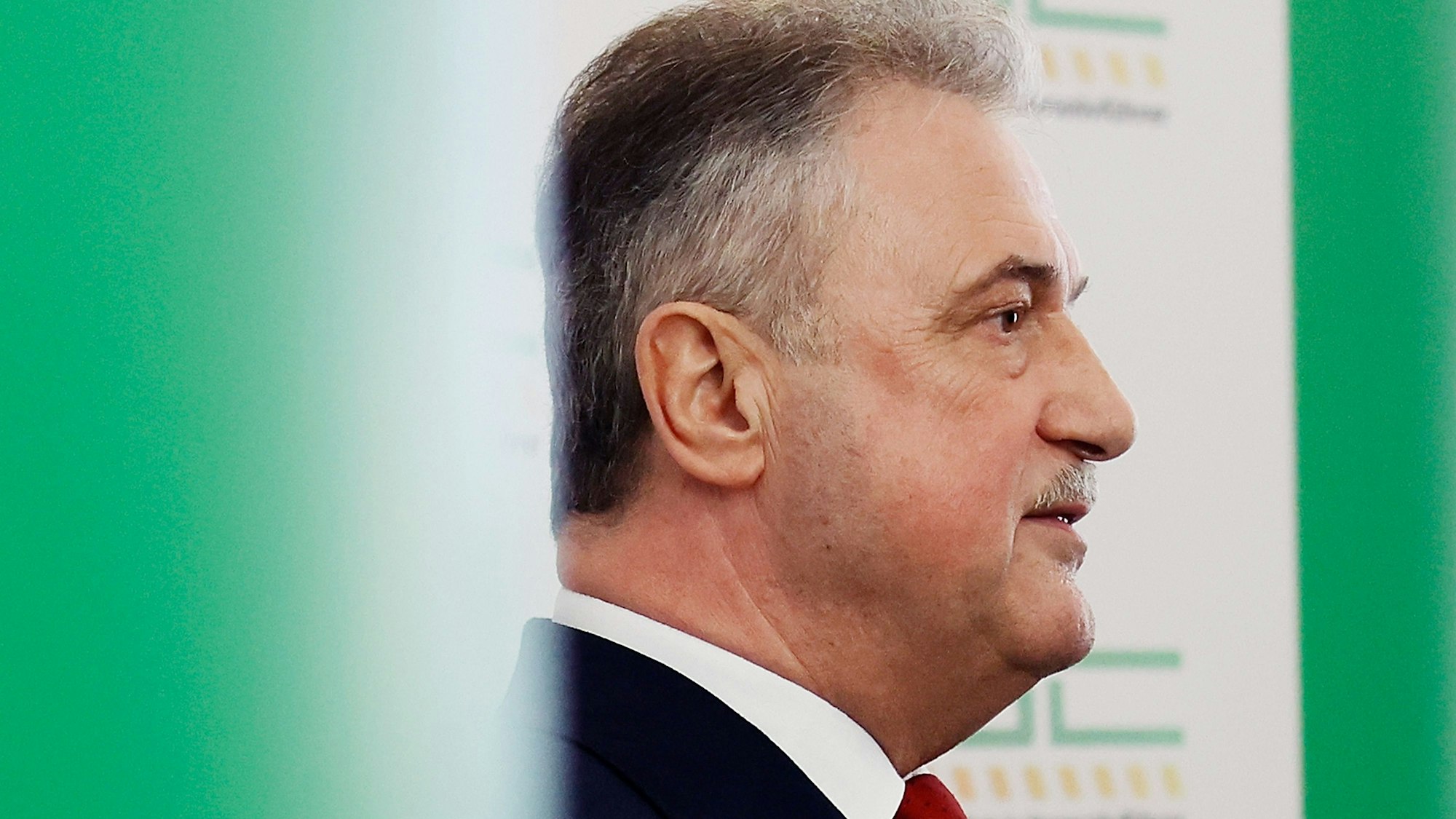 Claus Weselsky, Vorsitzender der Gewerkschaft Deutscher Lokomotivführer (GDL), ist im Profil zu sehen, während er bei einer Pressekonferenz spricht. Er steht vor einer grünen Wand, auf der das Logo der GDL schemenhaft zu erkennen ist.