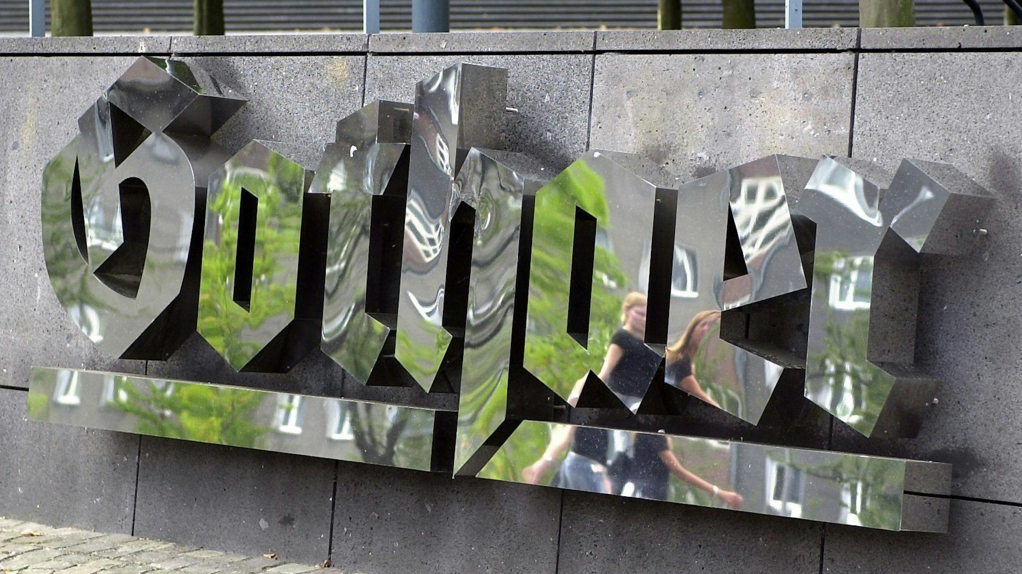 Passanten spiegeln sich am Freitag (18.07.2003) im geputzten Logo der Gothaer Versicherung in Köln. Der Versicherungskonzern gibt bei einer Bilanzpressekonferenz am Montag (21.07.2003) die Zahlen für das vergangene Jahr bekannt. Foto: Roland Scheidemann dpa/lnw |