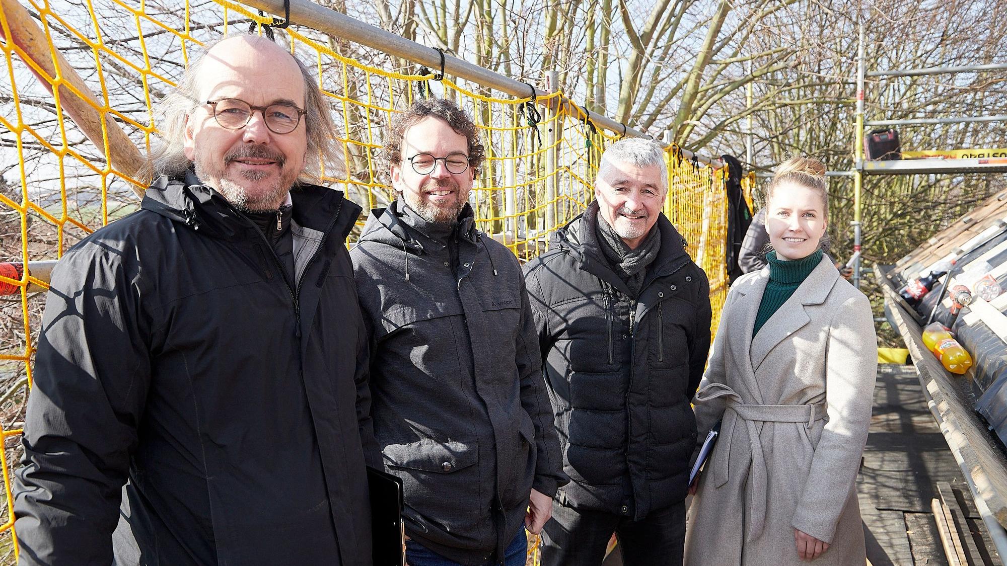Drei Männer und eine Frau stehen im Freien an der Baustelle der Kirche in Holzheim.