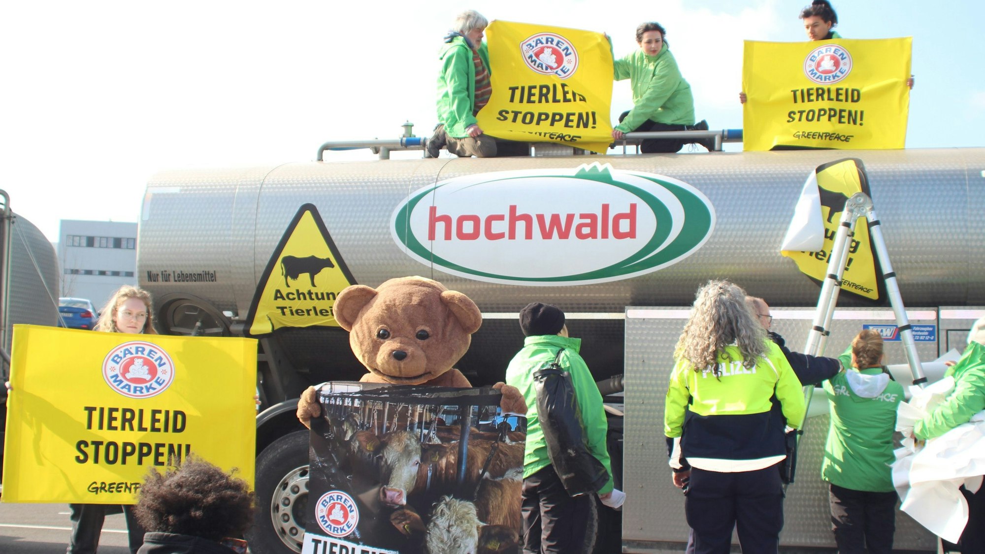 Aktivisten der Umweltschutzorganisation Greenpeace demonstrieren mit einem Teddybären und gelben Plakaten auf und vor einem Milchtransport-Lastwagen bei der Firma Hochwald in Obergartzem.