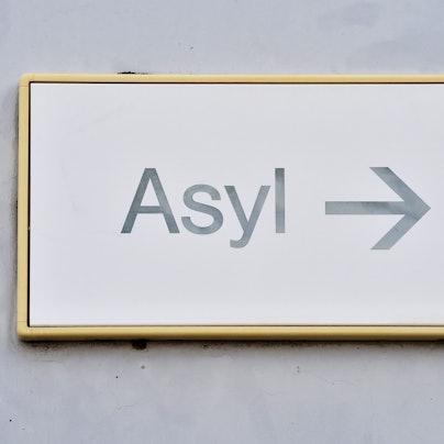 ARCHIV - 04.08.2014, Baden-Württemberg, Karlsruhe: Ein Schild mit der Aufschrift «Asyl» hängt in einer Erstaufnahme für Asylbewerber an einer Wand. (zu dpa: «Zahl der Asylbewerber zu Jahresstart deutlich gesunken») Foto: Uli Deck/dpa +++ dpa-Bildfunk +++