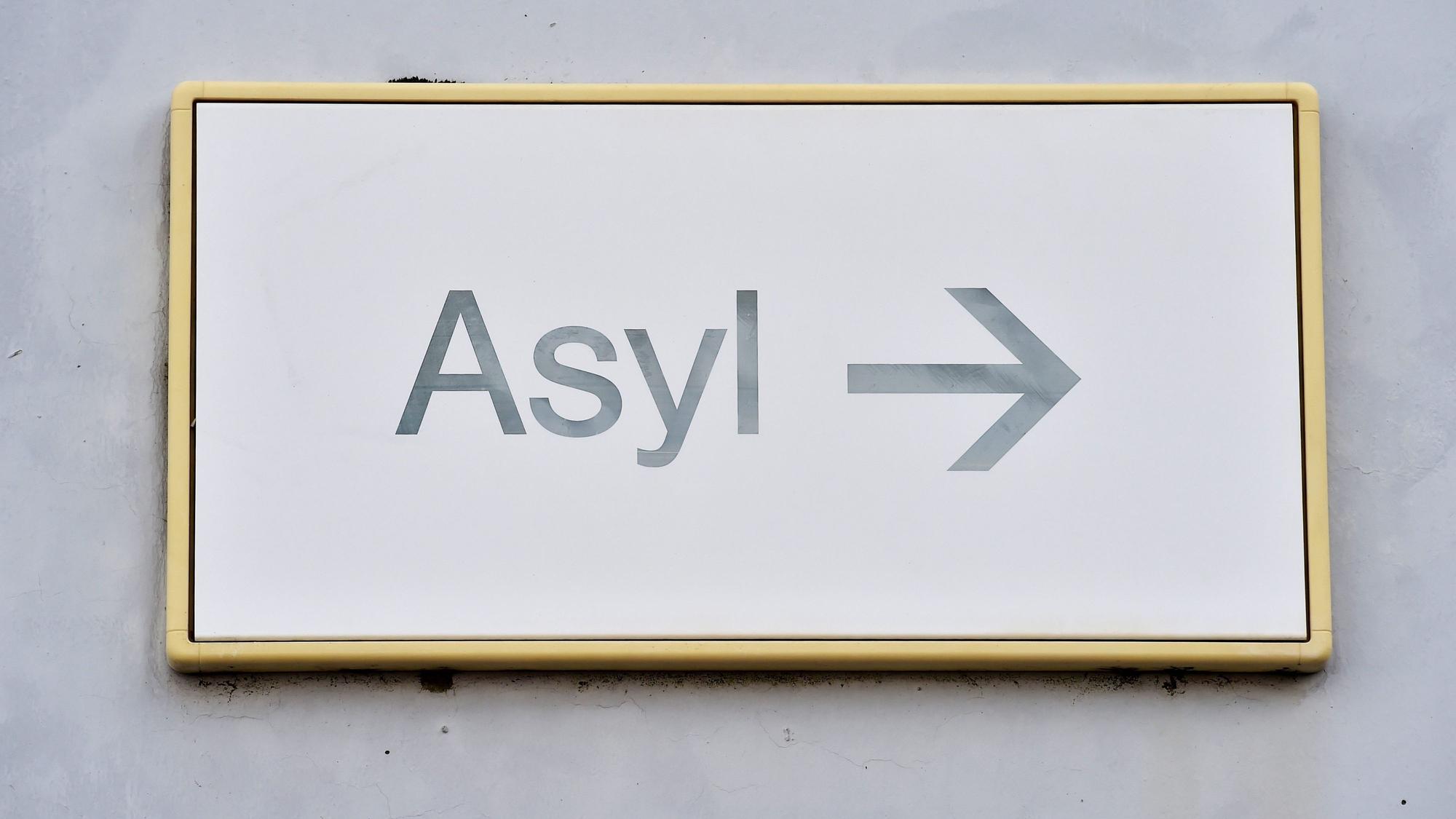 ARCHIV - 04.08.2014, Baden-Württemberg, Karlsruhe: Ein Schild mit der Aufschrift «Asyl» hängt in einer Erstaufnahme für Asylbewerber an einer Wand. (zu dpa: «Zahl der Asylbewerber zu Jahresstart deutlich gesunken») Foto: Uli Deck/dpa +++ dpa-Bildfunk +++