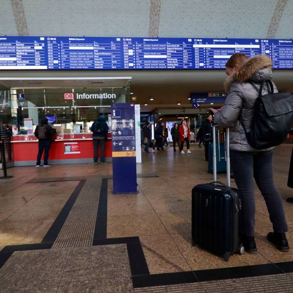 Im Foyer des HBF schauen sich Pendler die Abfahrtstafel an.
